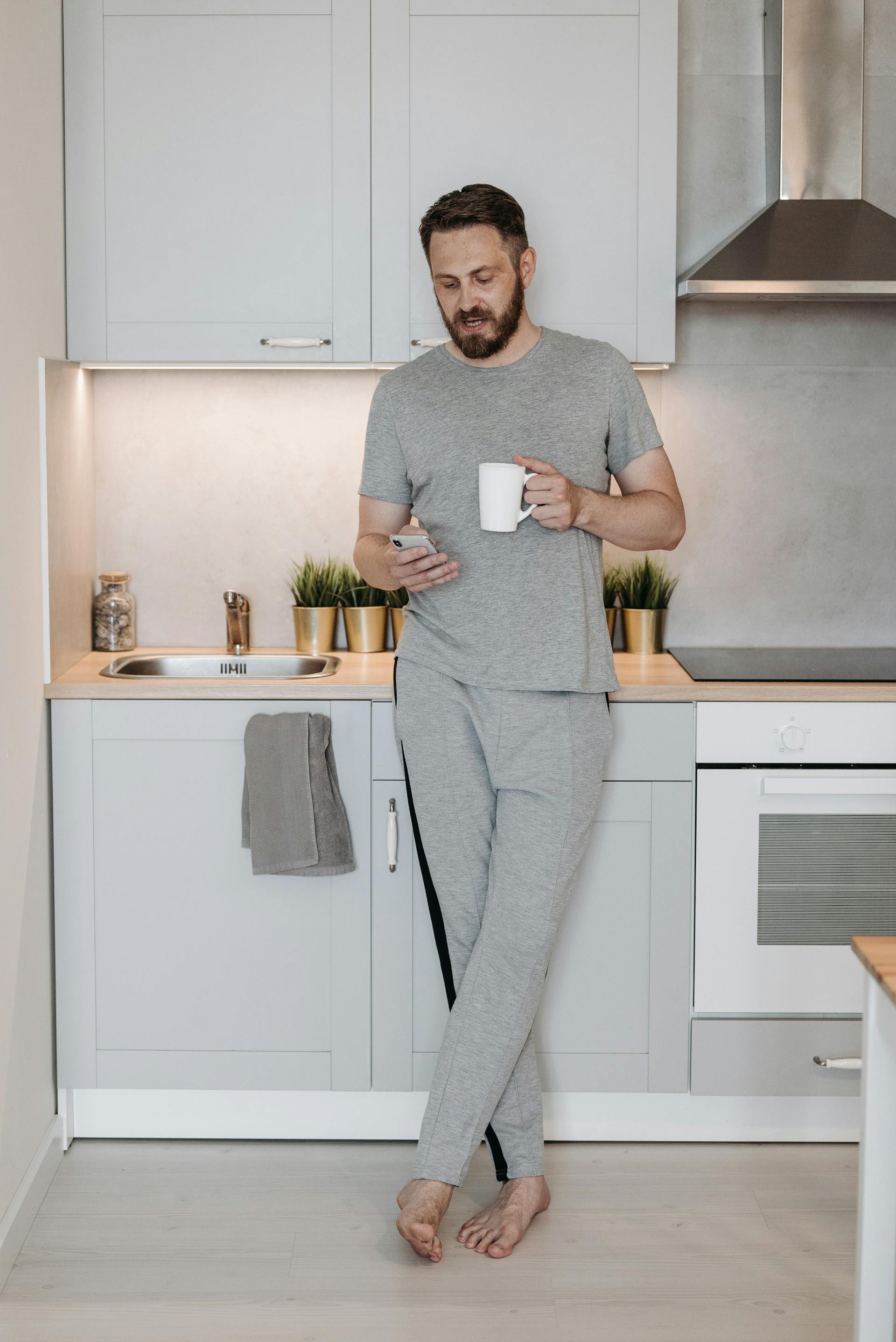 Un hombre mirando el móvil en una cocina | Fuente: Pexels