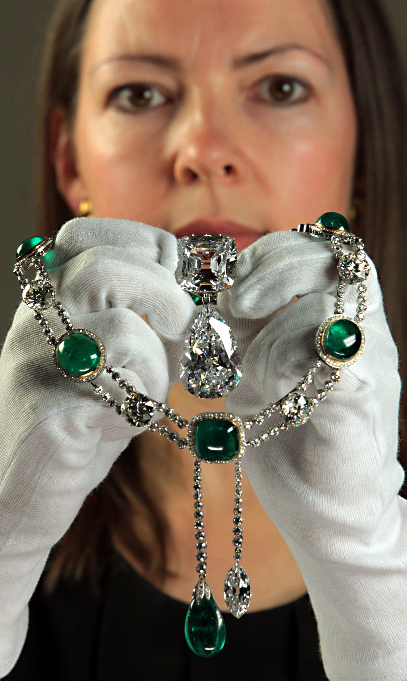La curadora de la exposición Caroline de Guitaut sostiene el broche Cullinan y el colgante del collar Cullinan V en la Queens Gallery en el Palacio de Buckingham. | Foto: Getty Images