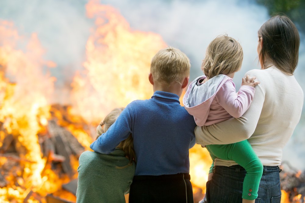 Madre de familia con hijos observando la casa en llamas. Fuente: Shutterstock