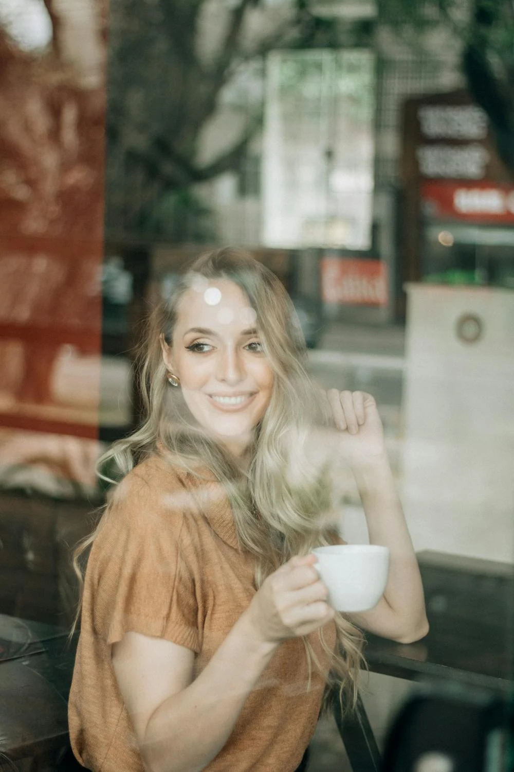 Una mujer sonriente tomando café | Fuente: Pexels