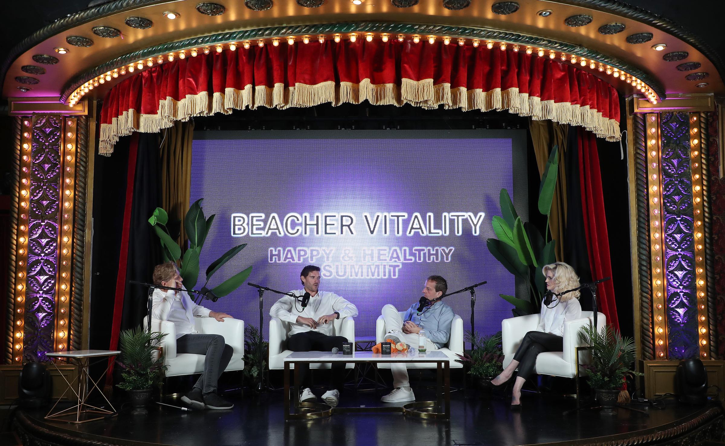 Bajo las ornamentadas luces del escenario del Hollywood Roosevelt, Christopher Schwarzenegger se une a otros ponentes para un debate centrado en la salud y el bienestar. El escenario del panel cuenta con una iluminación vibrante y una decoración tropical, que marcan el tono del tema edificante del día.