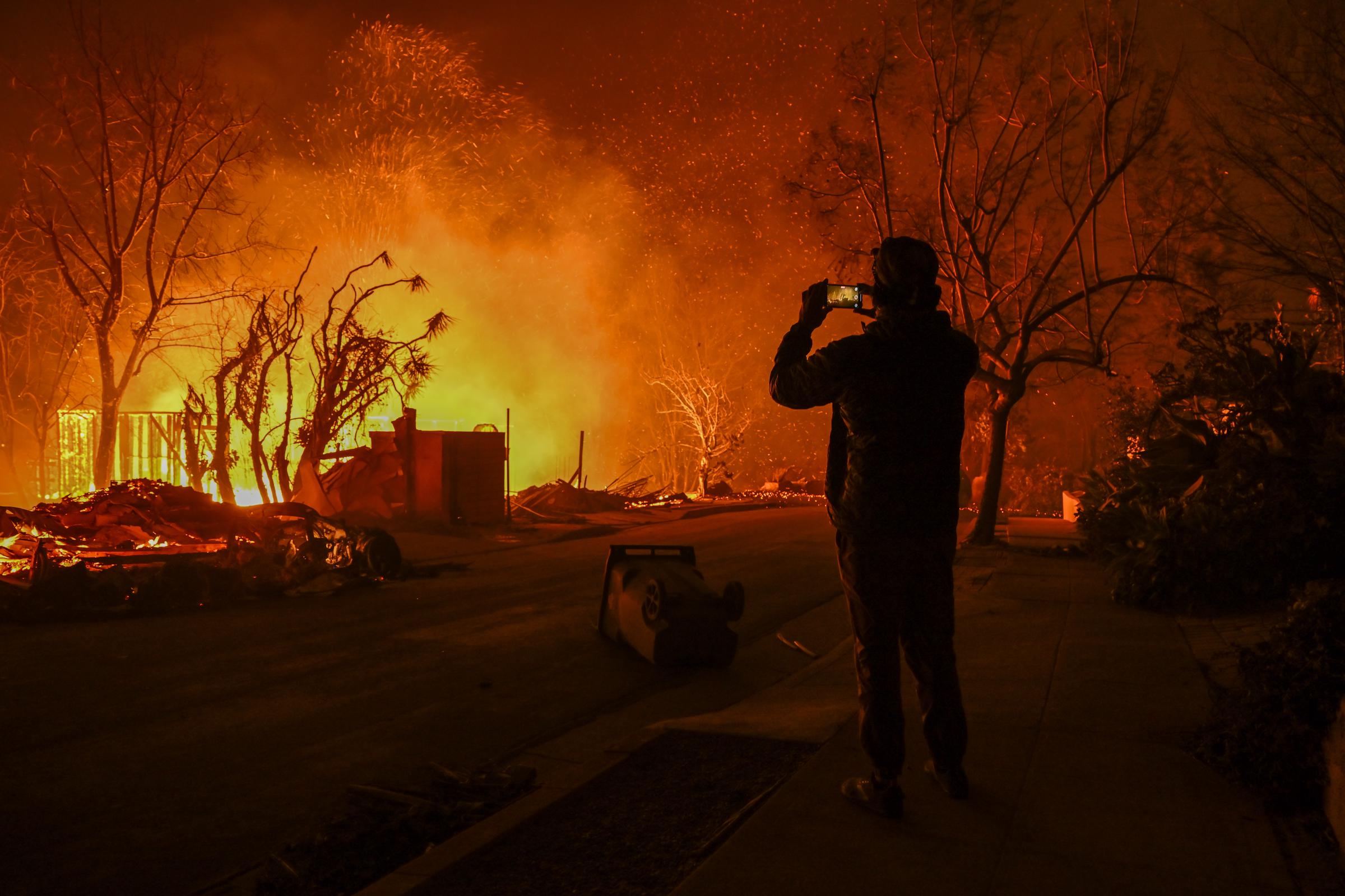 Un civil grabando la destrucción de un incendio forestal en Pacific Palisades, California, el 8 de enero de 2025. | Fuente: Getty Images