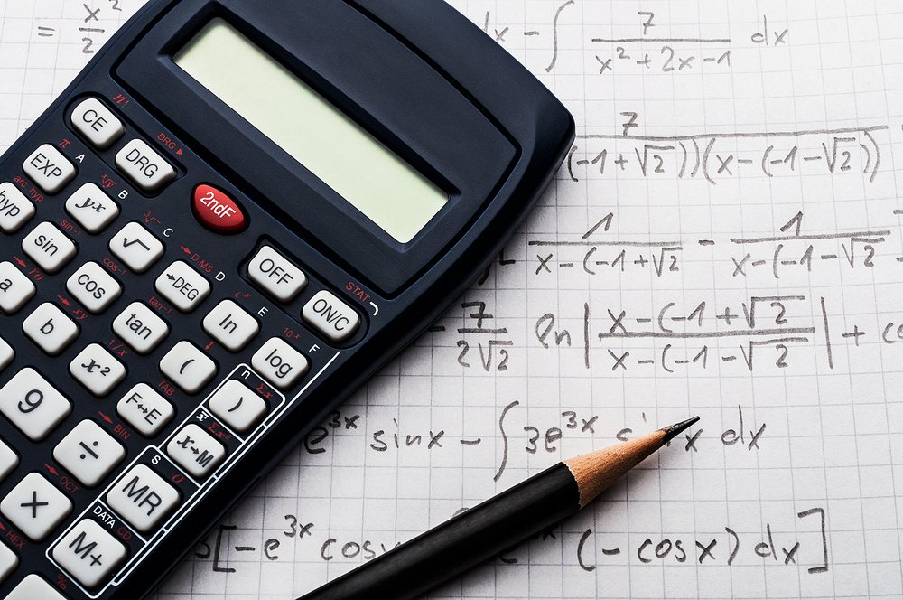 Calculadora y lápiz sobre una hoja de papel con fórmulas matemáticas. Fuente: Shutterstock