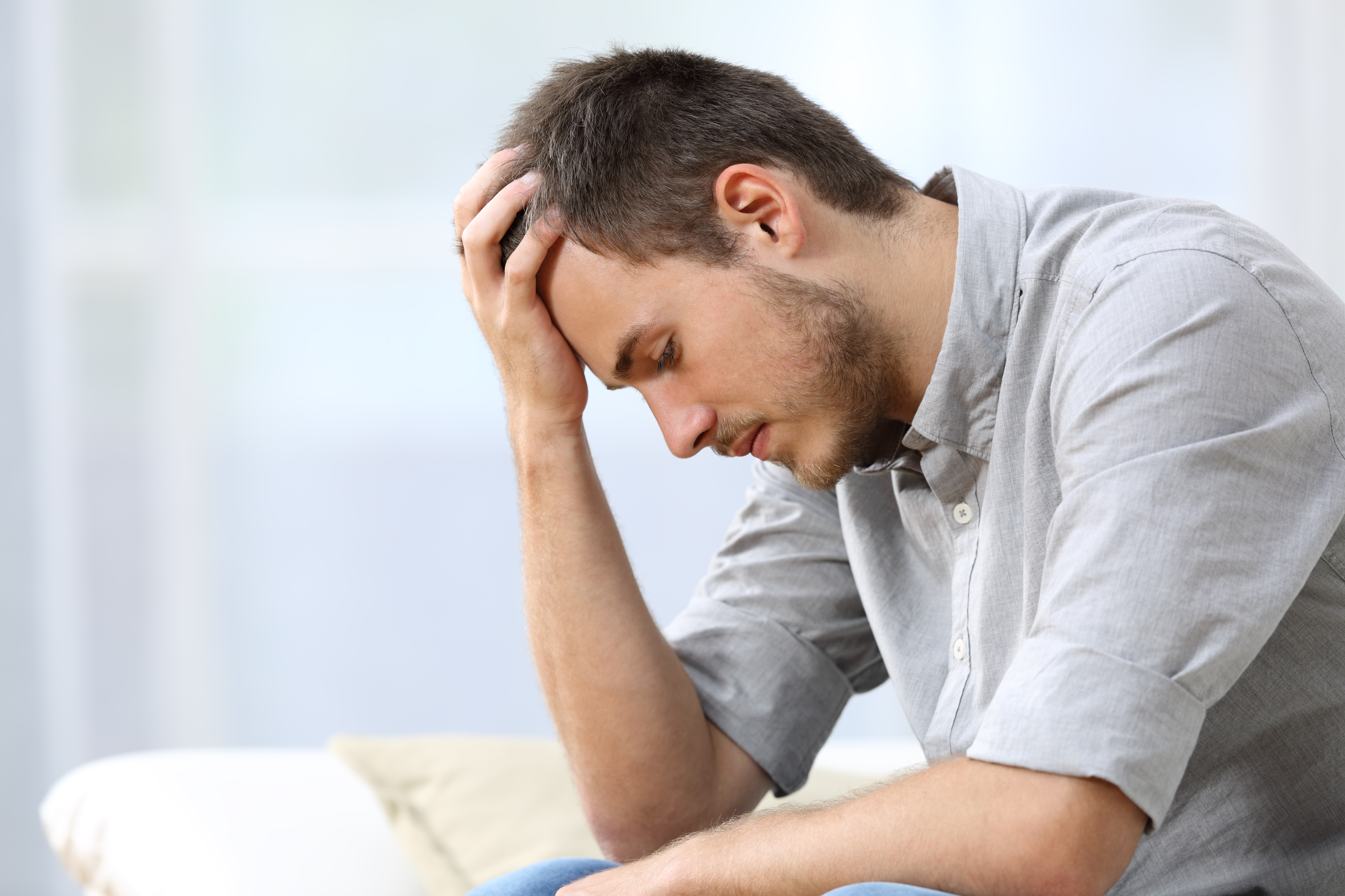 Hombre triste sentado en el sofá de su casa | Fuente: Getty Images