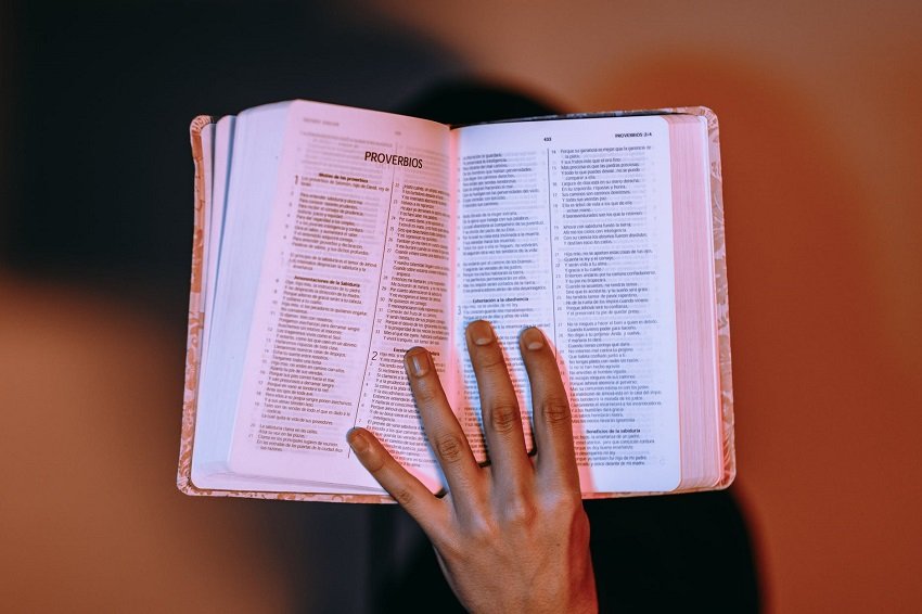 Mano con la Biblia abierta en Proverbios. | Foto: Pexels