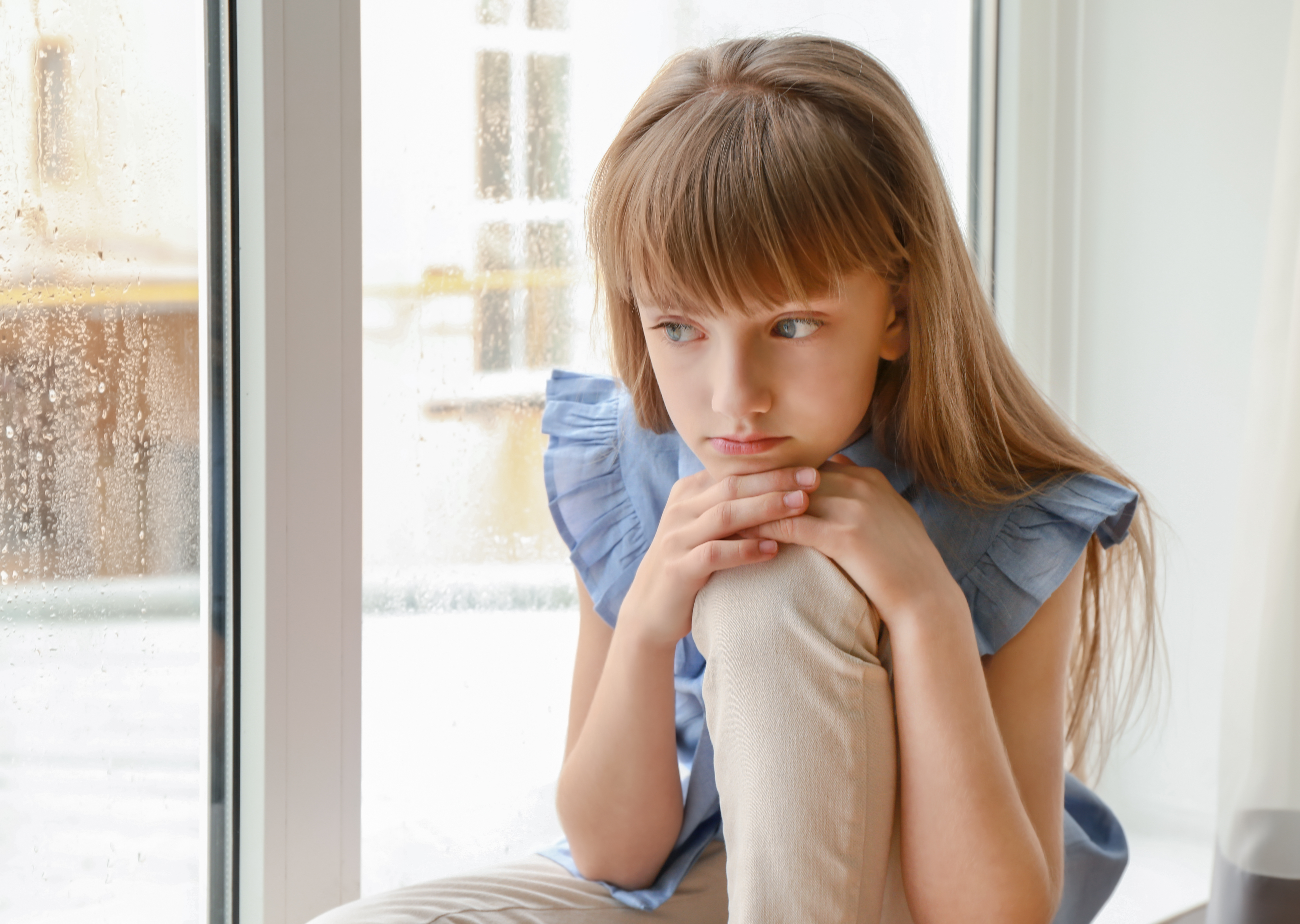 Niña enfurruñada junto a la ventana | Foto: Shutterstock