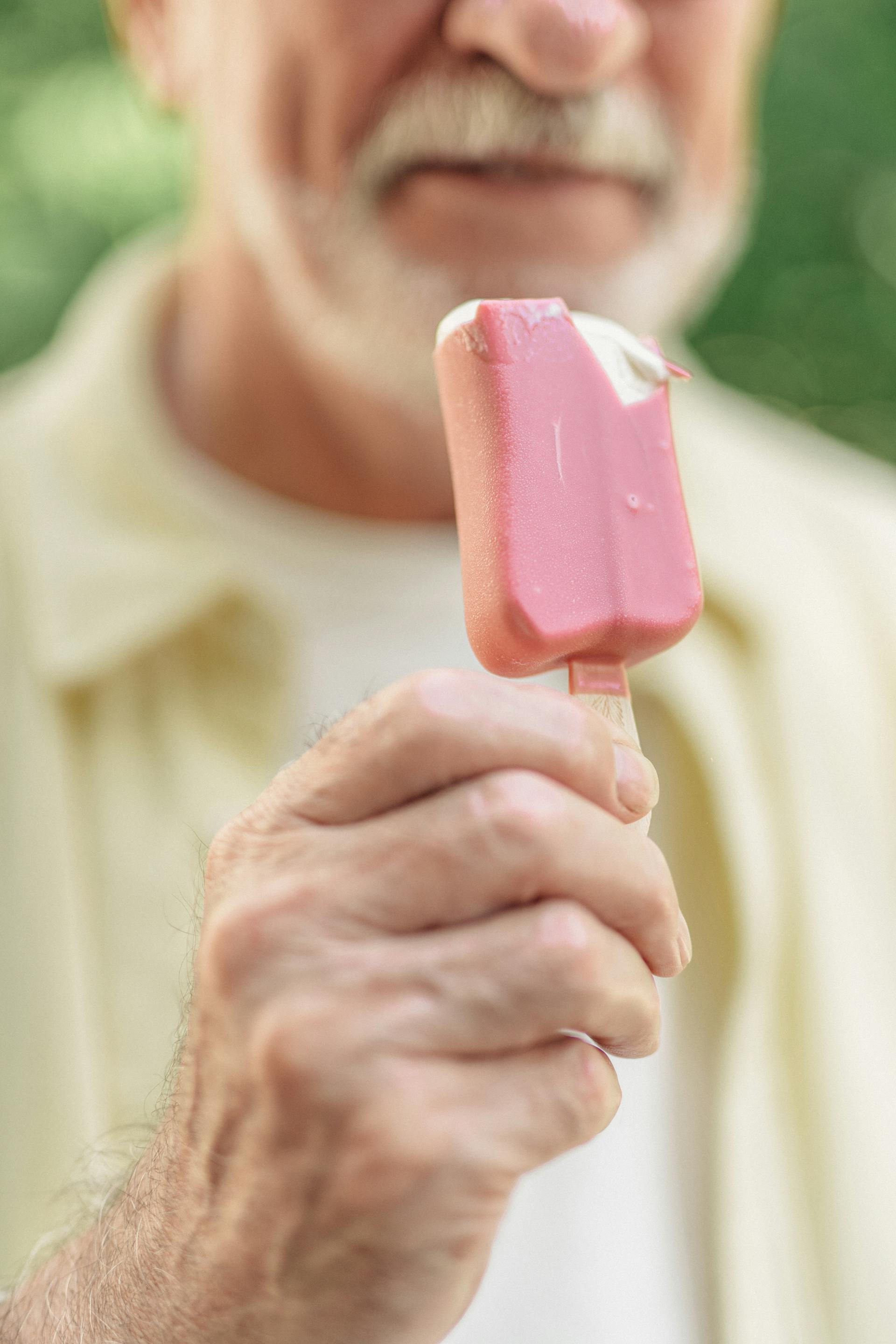 Un hombre mayor con una paleta helada en la mano | Fuente: Pexels