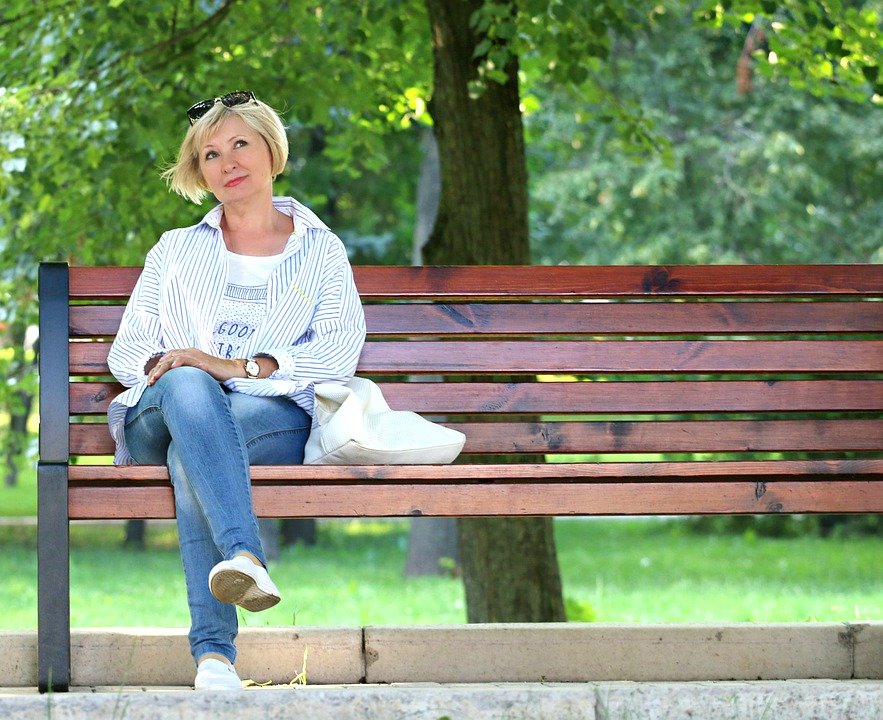 Mujer sentada en un banquillo mientras está pensativa en un parque. | Imagen: Pixabay