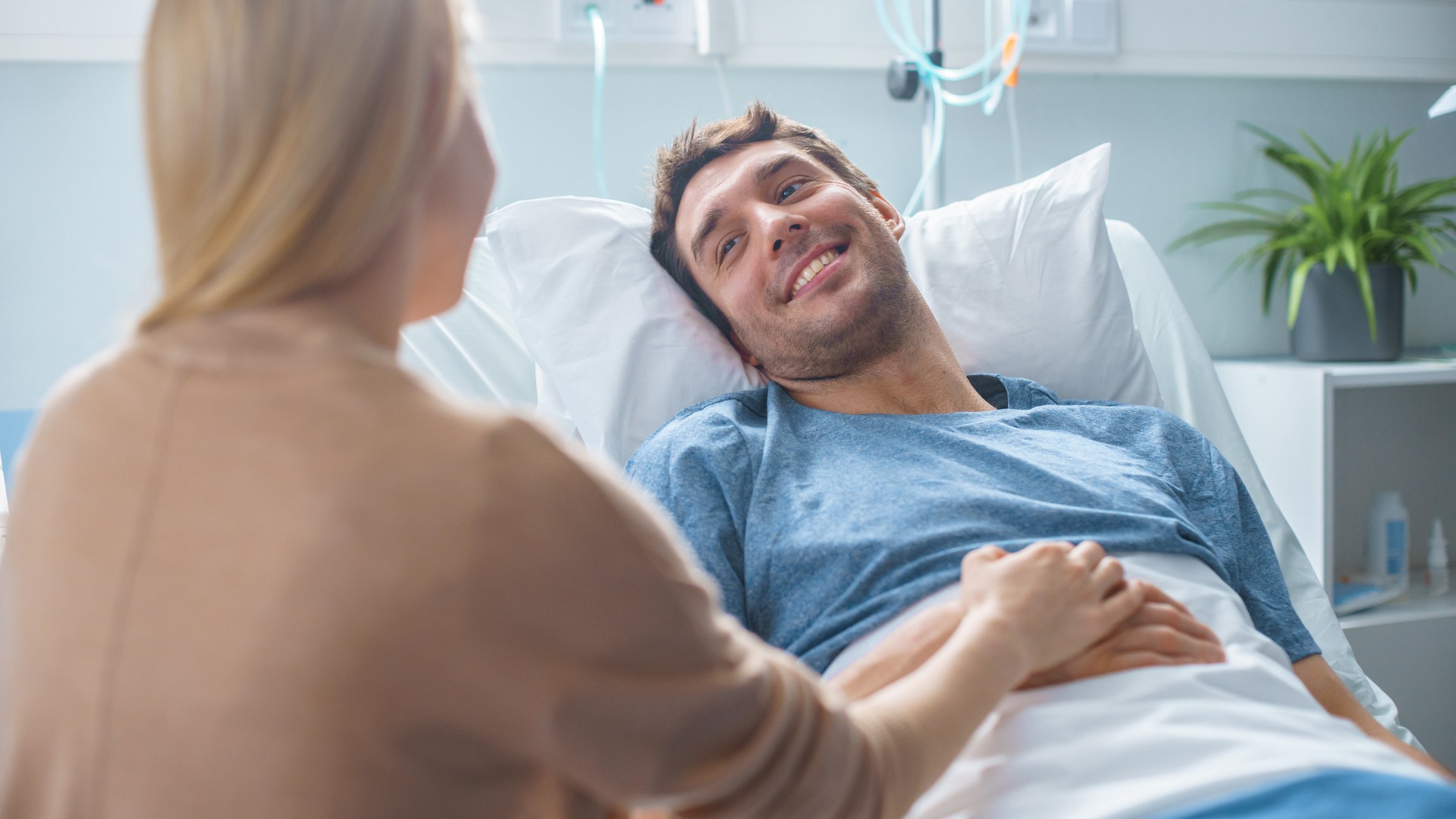 Un hombre en la camilla de un hospital, sonrie a la mujer que lo visita. | Foto: Getty Images
