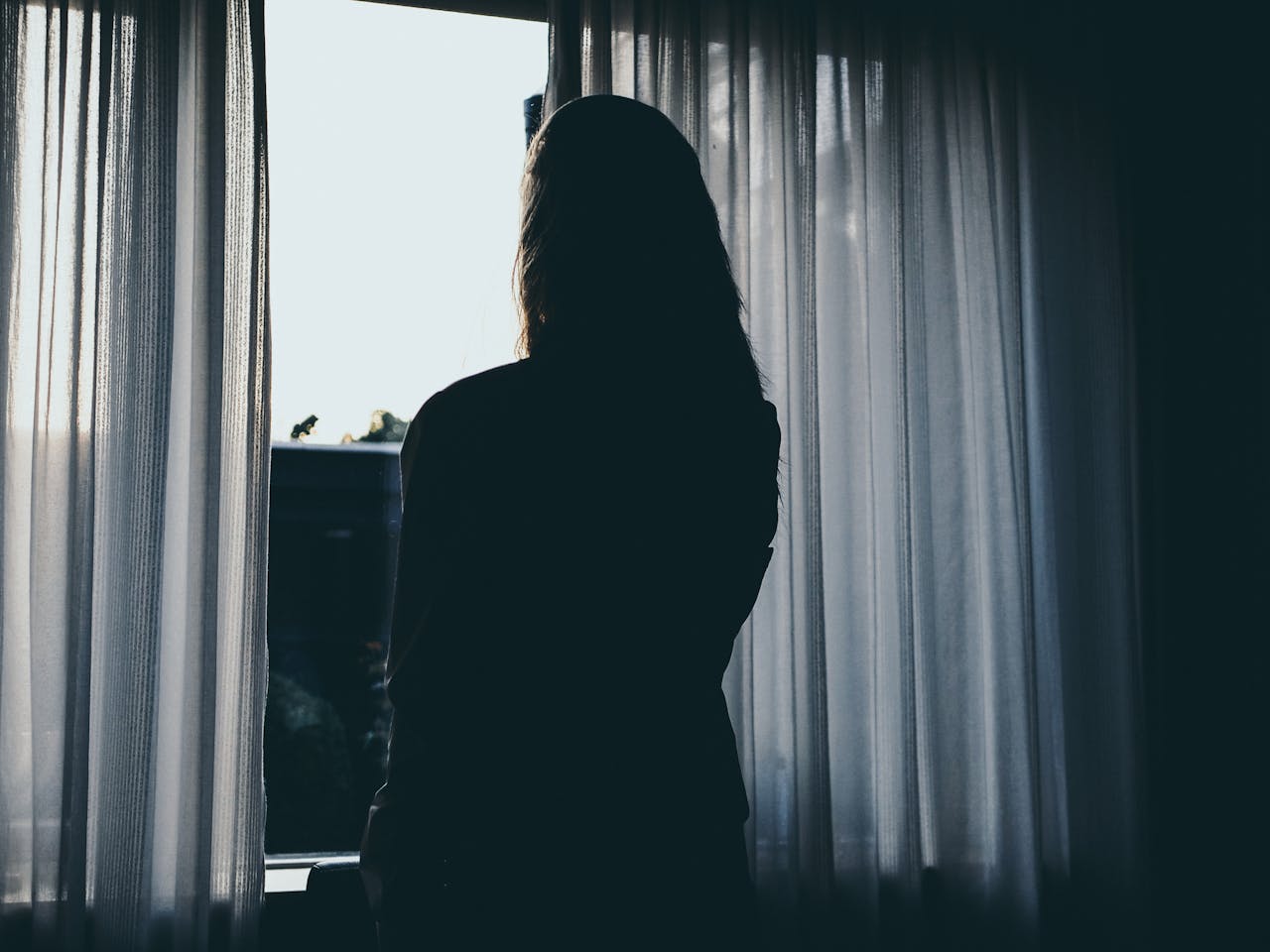 Silueta de una mujer de pie junto a la ventana | Fuente: Pexels