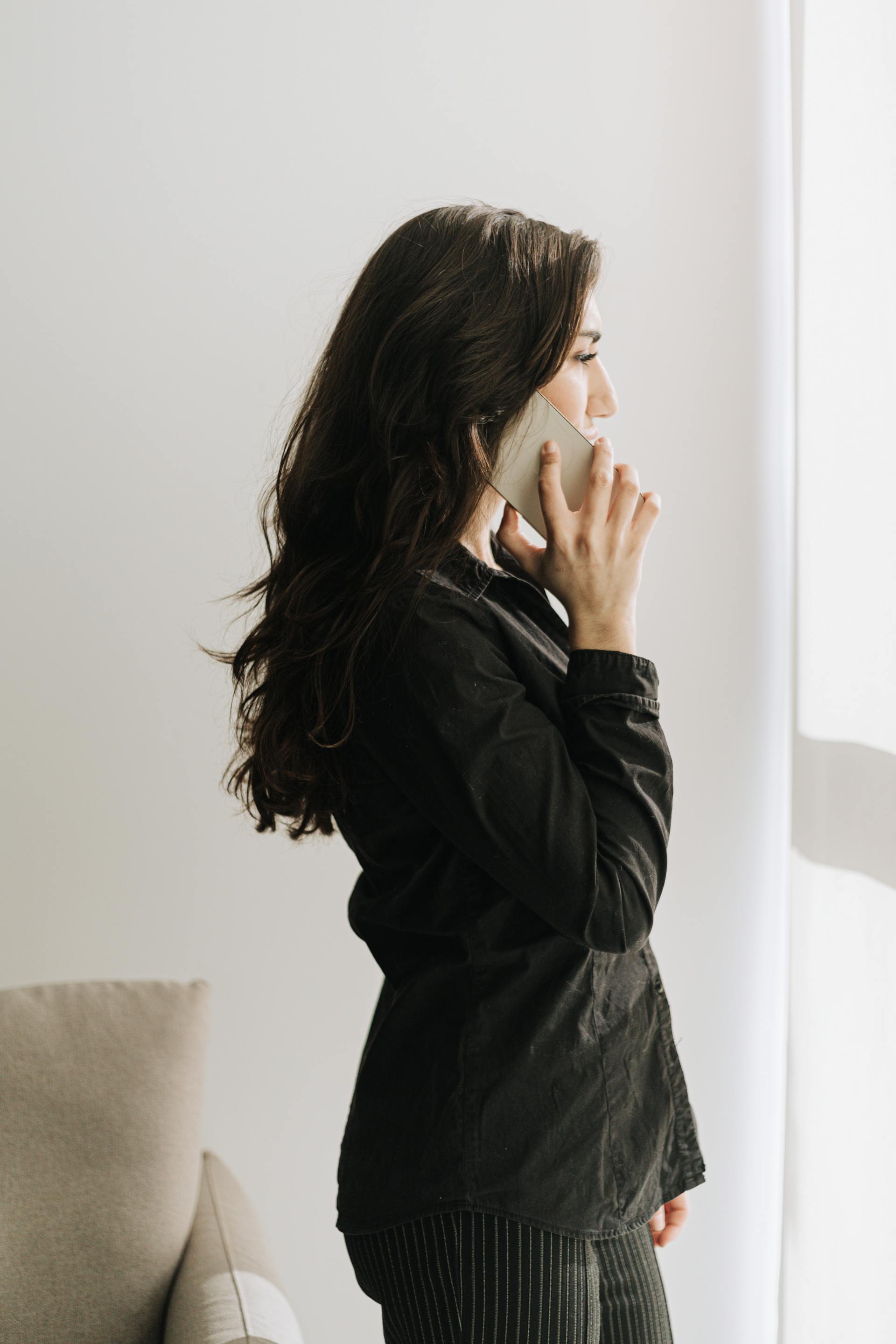 Una mujer hablando por teléfono junto a una ventana | Fuente: Pexels