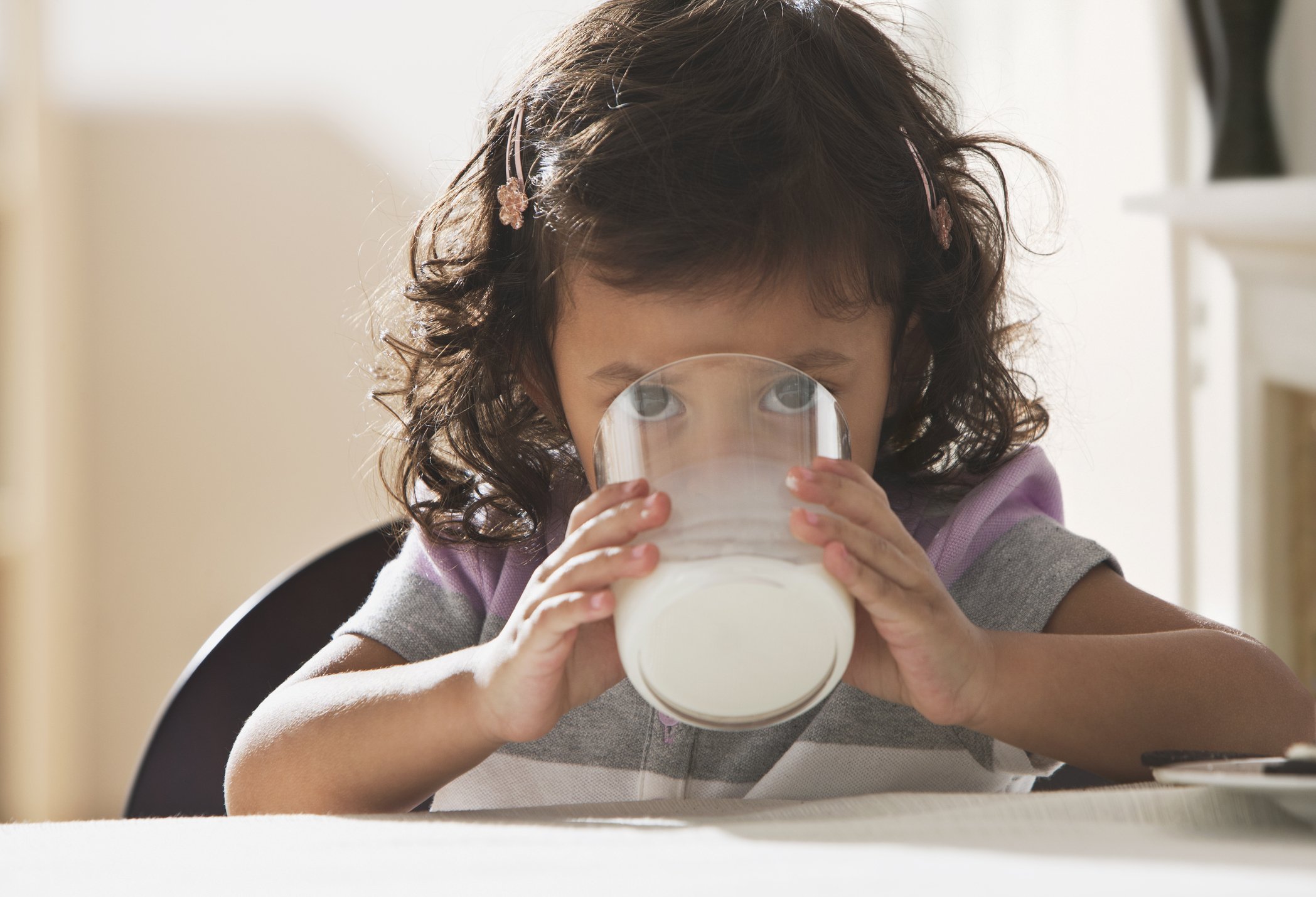 Niña molesta bebiendo un vaso de leche | Foto: Getty Images