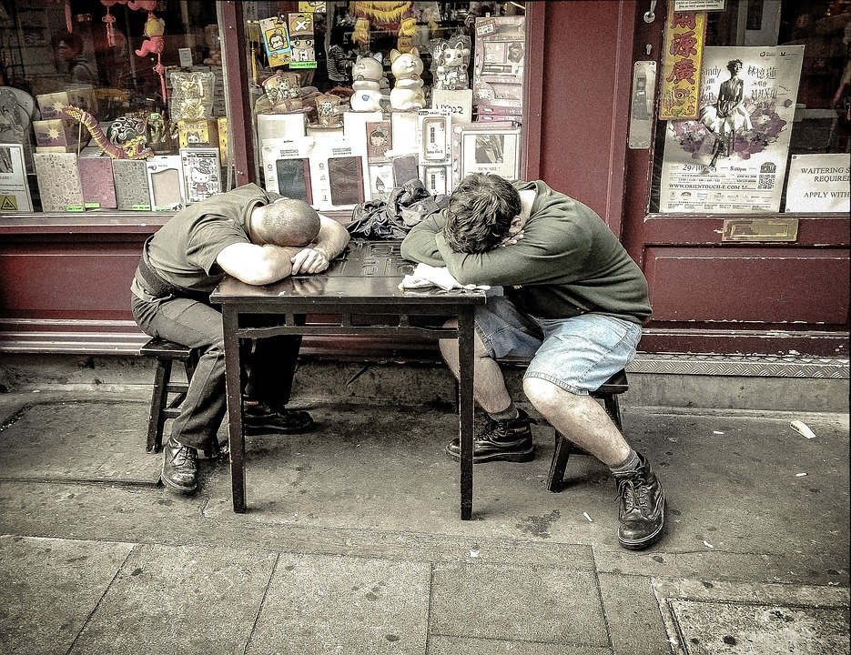 Dos jóvenes exhaustos recostados en una mesa. | Imagen: Pixabay