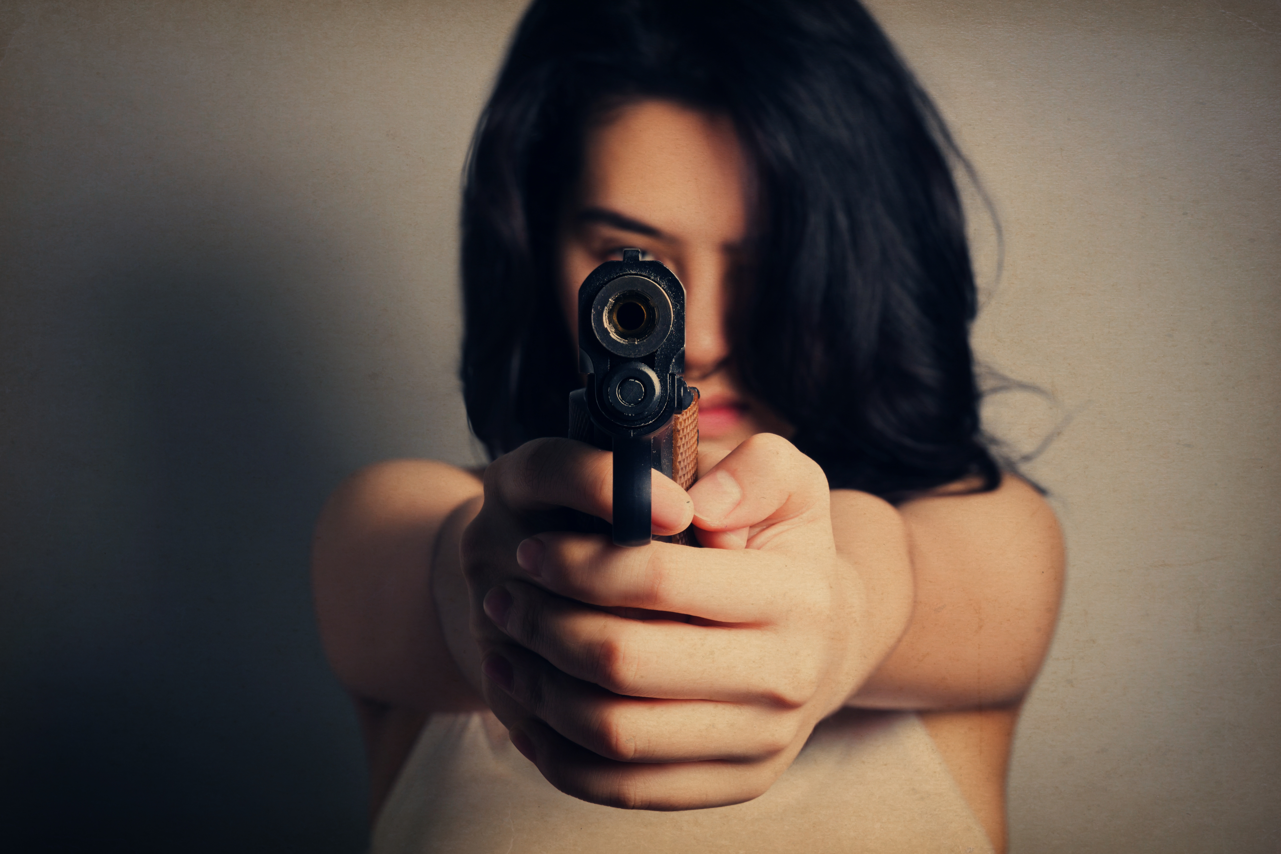Mujer apuntando con una pistola | Fuente: Shutterstock