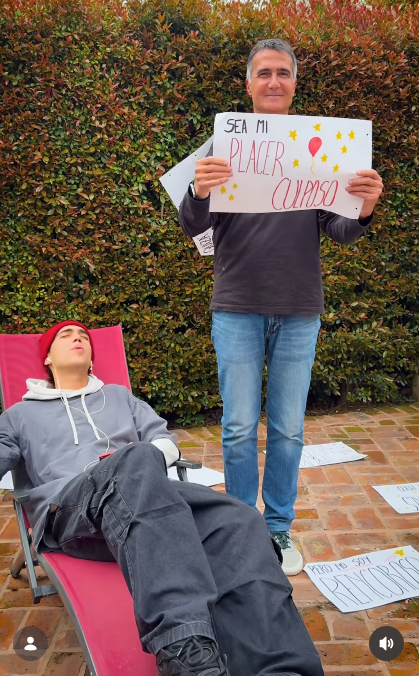 Antonio Laje sostuvo con una sonrisa un cartel con la frase "SEA MI PLACER CULPOSO" adornado con un globo y estrellas, participando en el divertido clip de promoción de su hijo Ezequiel Laje (Leish). Mientras el periodista exhibía el letrero de pie, el joven cantante permanecía recostado en una reposera con auriculares y gorro de lana rojo, inmerso en su música. | Fuente: Instagram/leish.ar