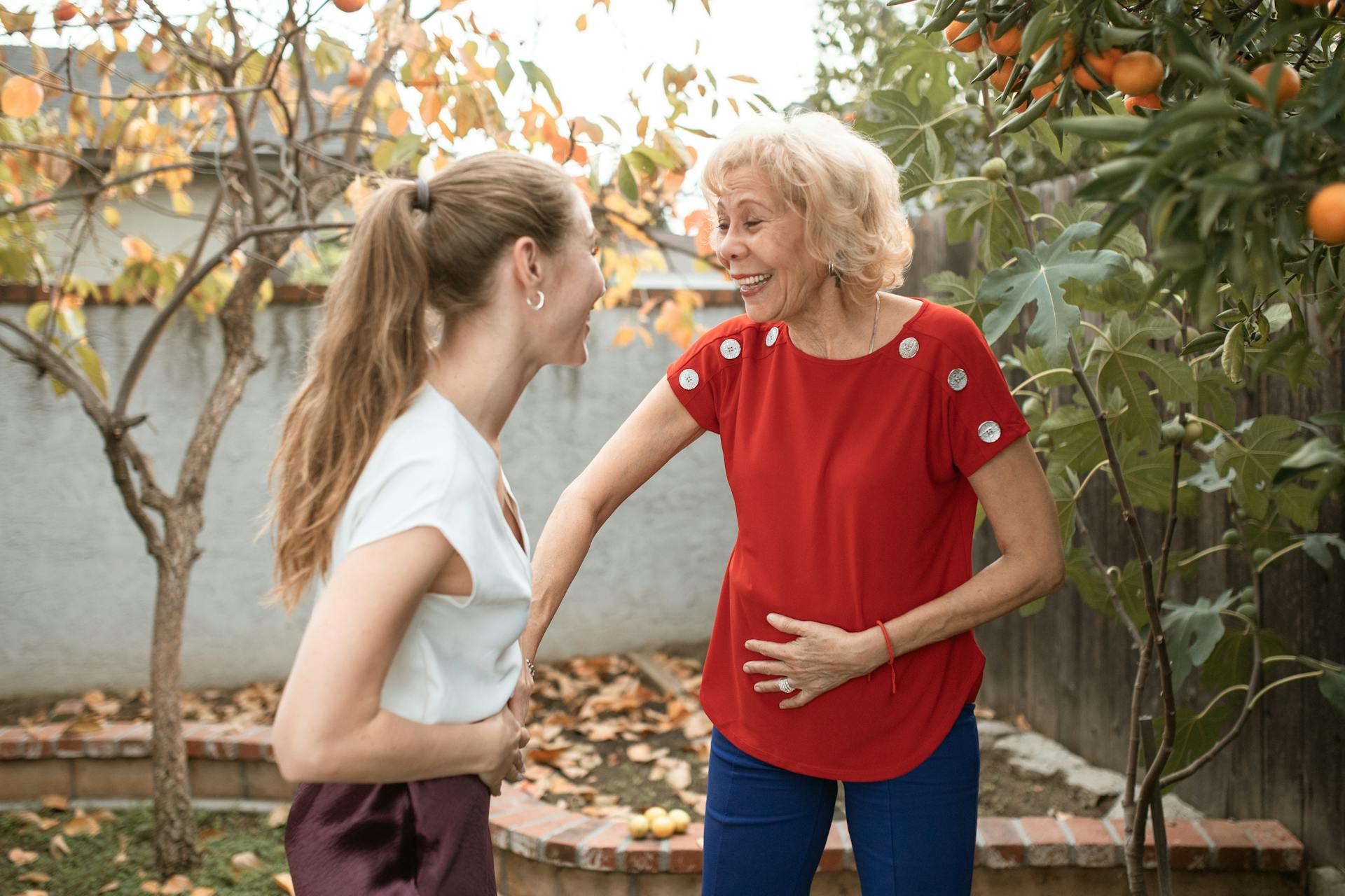 Una mujer rubia con coleta charlando con una señora mayor en el jardín | Fuente: Pexels