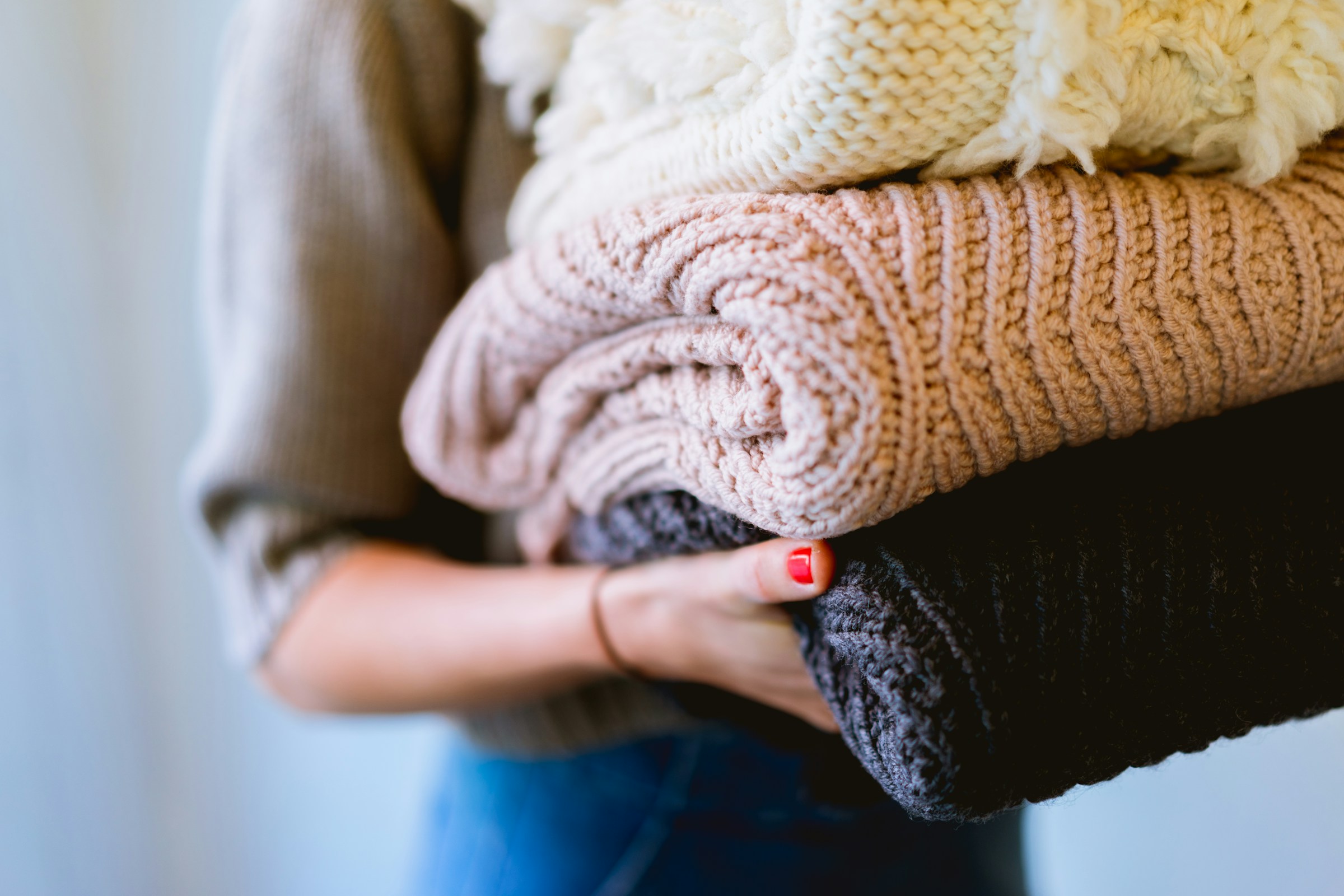 Mujer cargando una pila de prendas de lana | Fuente: Unsplash