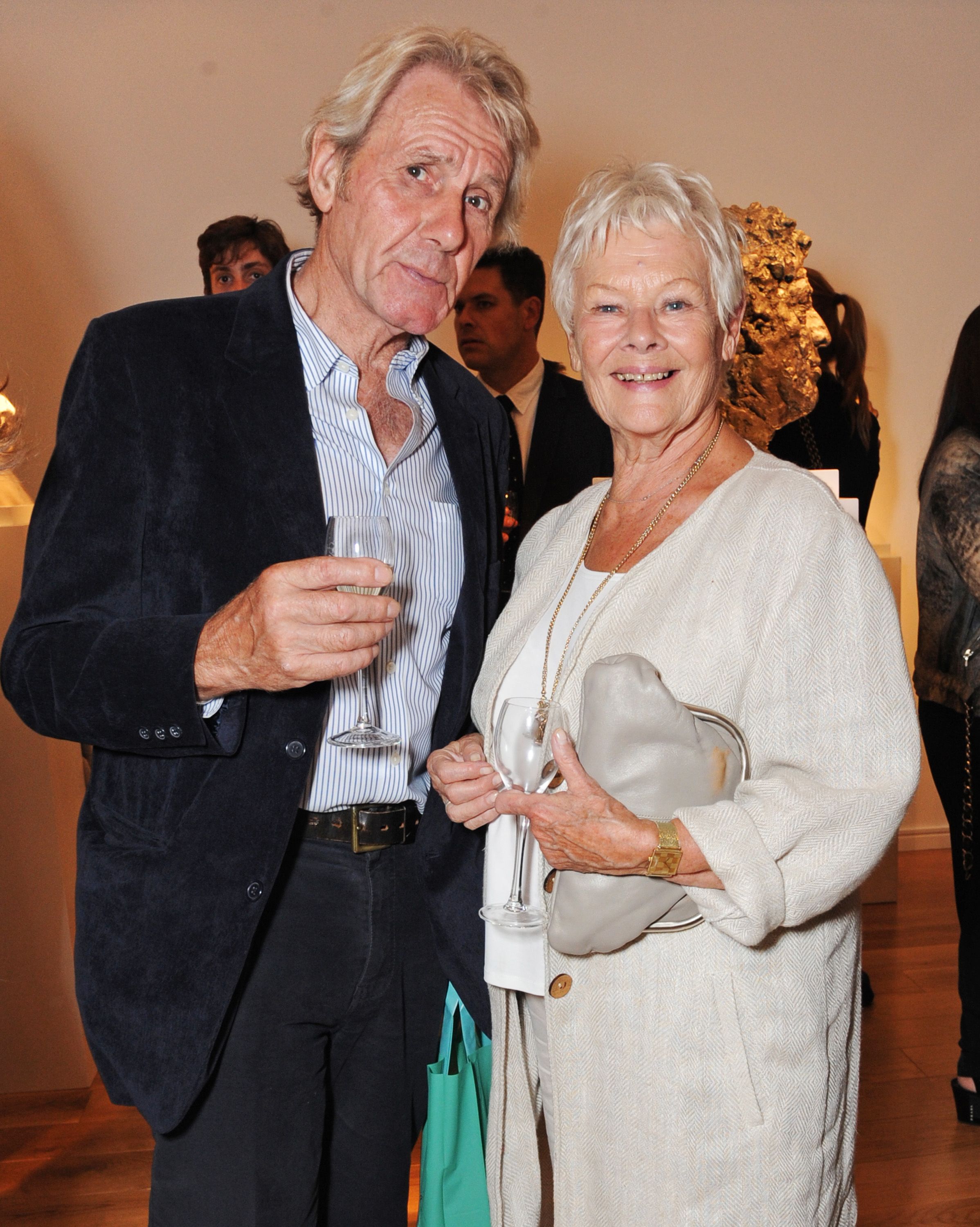 Judi Dench y David Mills en la exposición debut de Nicole Farhi 'From The Neck Up' en 2014, en Londres, Inglaterra. | Foto: Getty Images