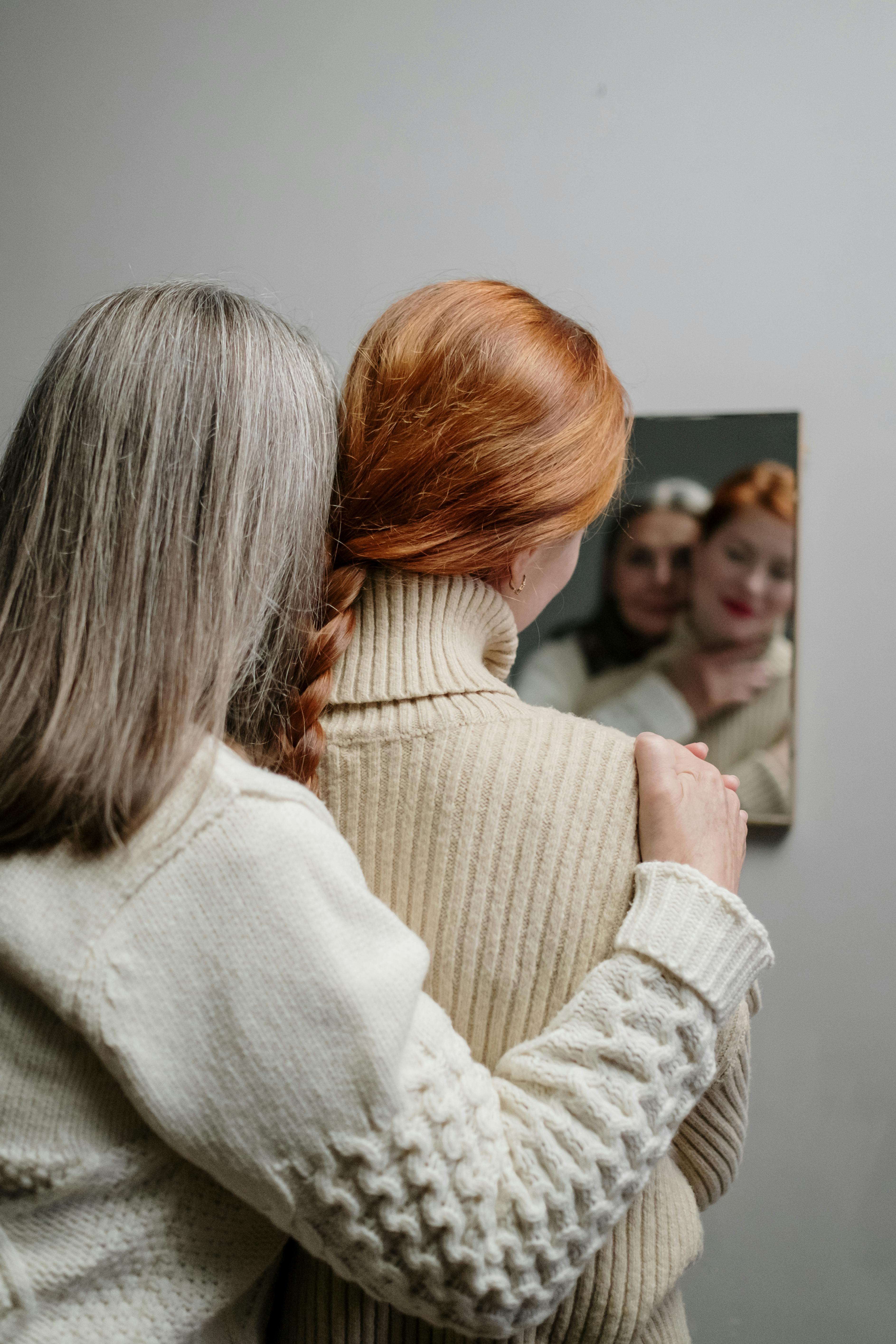 Una mujer mayor abrazando a otra más joven mientras se mira en el espejo | Fuente: Pexels