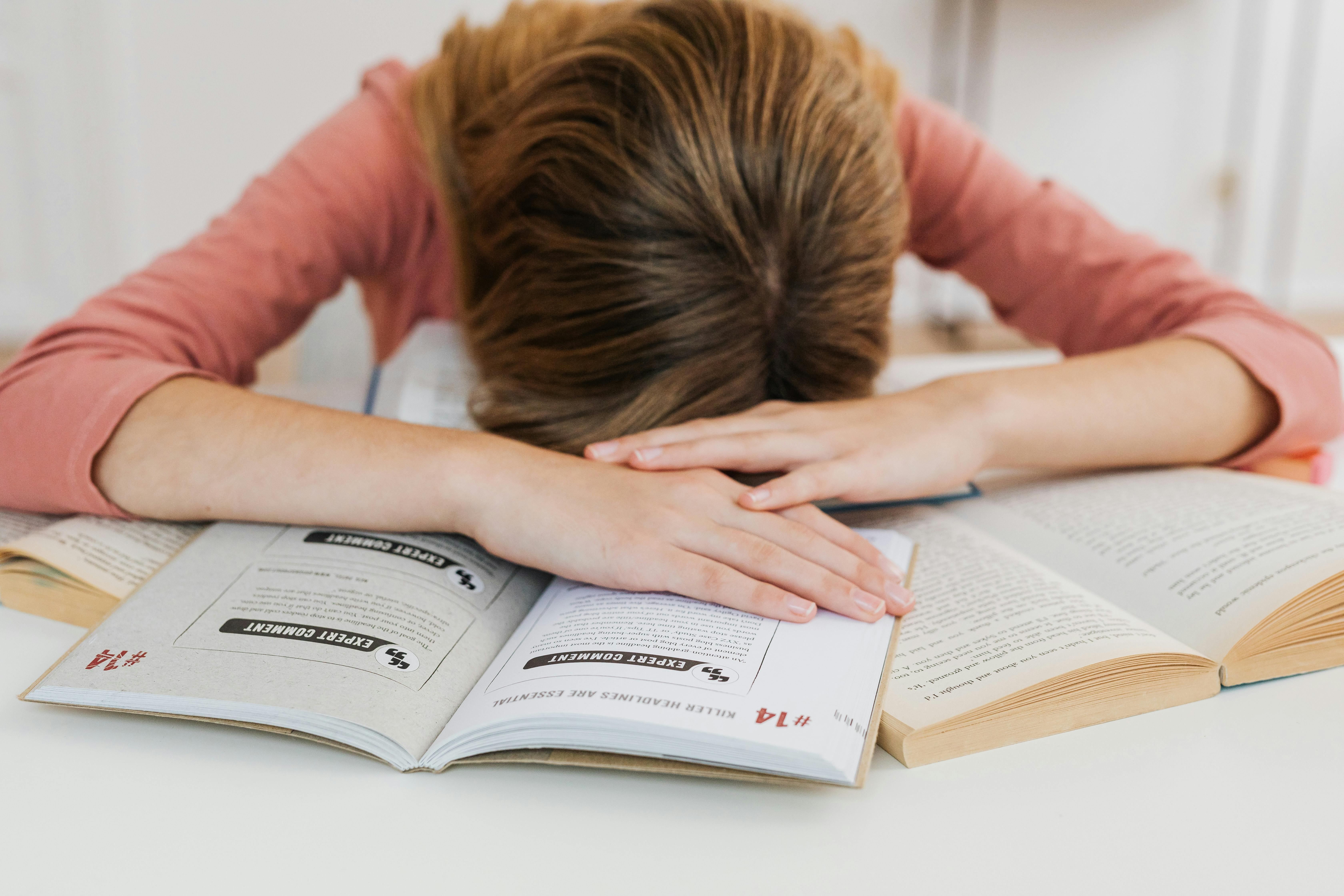 Una ragazza stressata sdraiata sui suoi libri | Fonte: Pexels