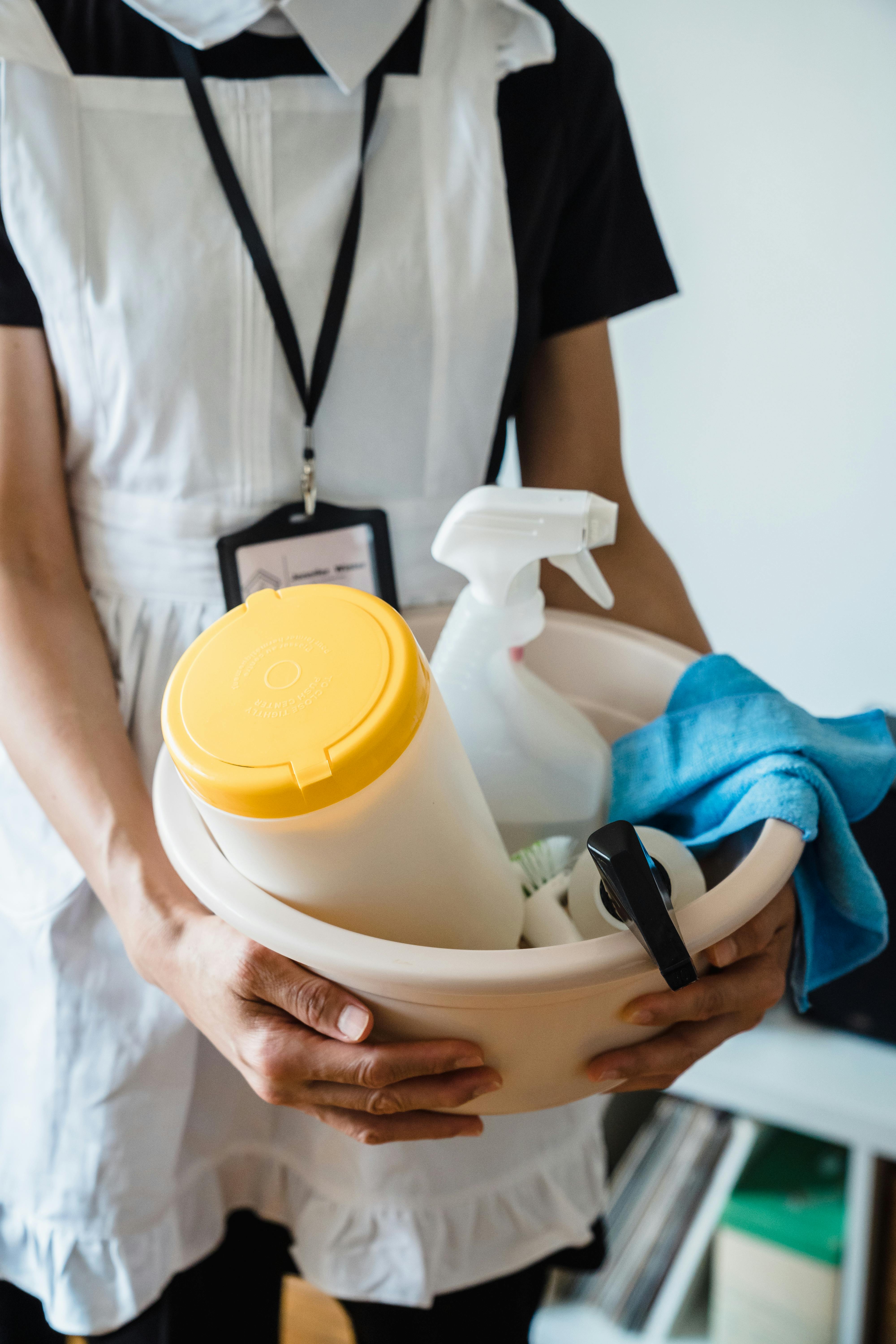 Mujer sujetando una palangana de plástico con material de limpieza | Fuente: Pexels