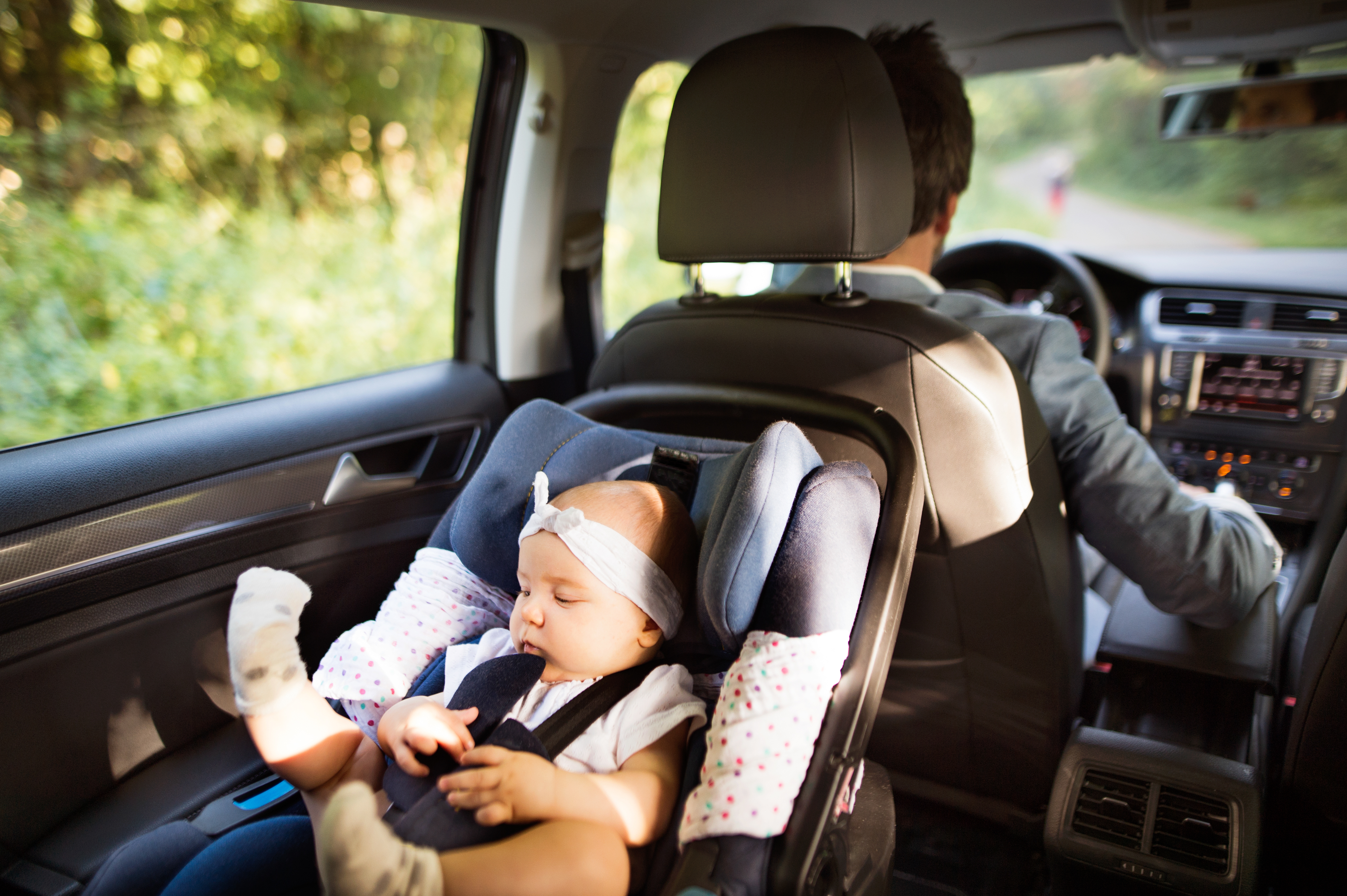 Un hombre conduce mientras un niño duerme en el asiento trasero | Foto: Shutterstock