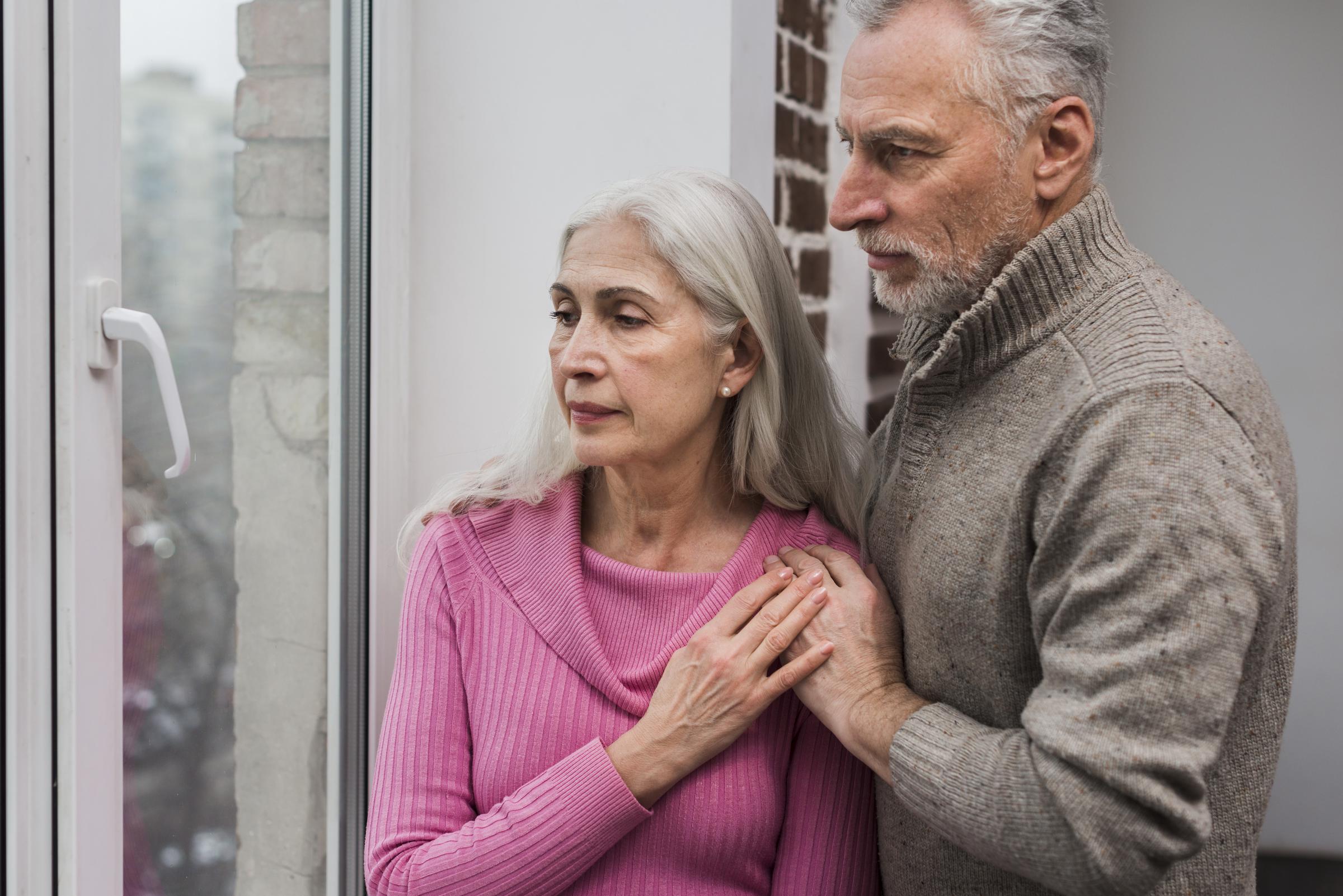 Una pareja de ancianos mirando por la ventana | Fuente: Freepik