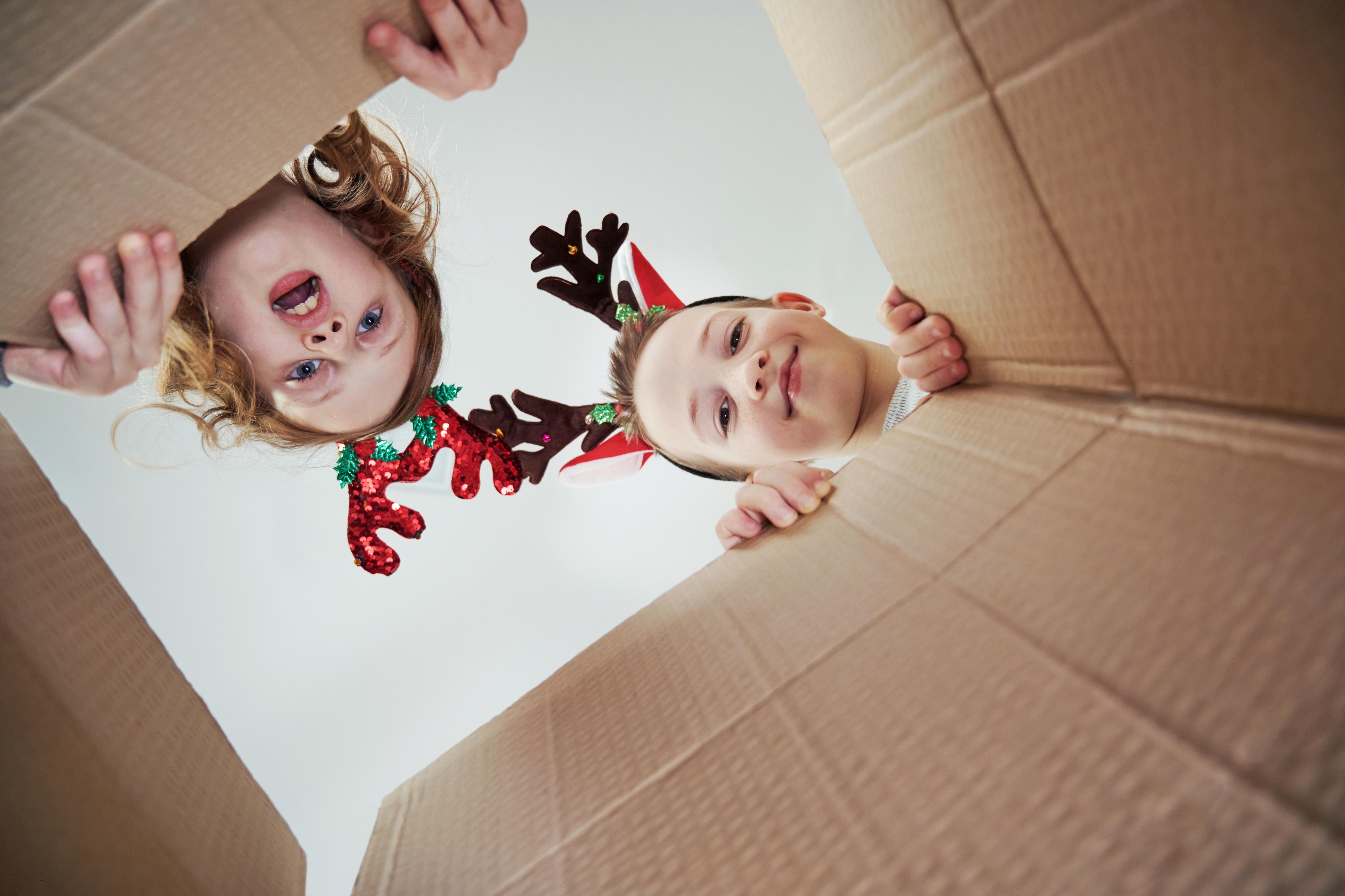 Un niño y una niña mirando dentro de una caja de cartón. | Foto: Shutterstock