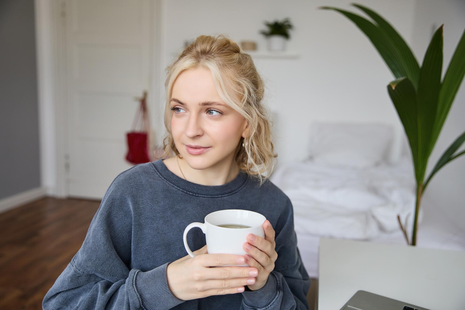 Una mujer mirando a su lado mientras bebe café | Fuente: Freepik