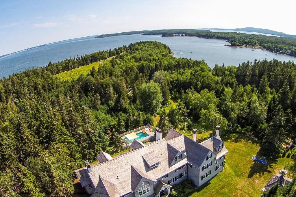Una vista aérea muestra esta amplia vivienda rodeada de un frondoso bosque, con su ubicación frente al mar y las aguas cercanas extendiéndose hasta donde alcanza la vista. | Fuente: Facebook/LegacySIR