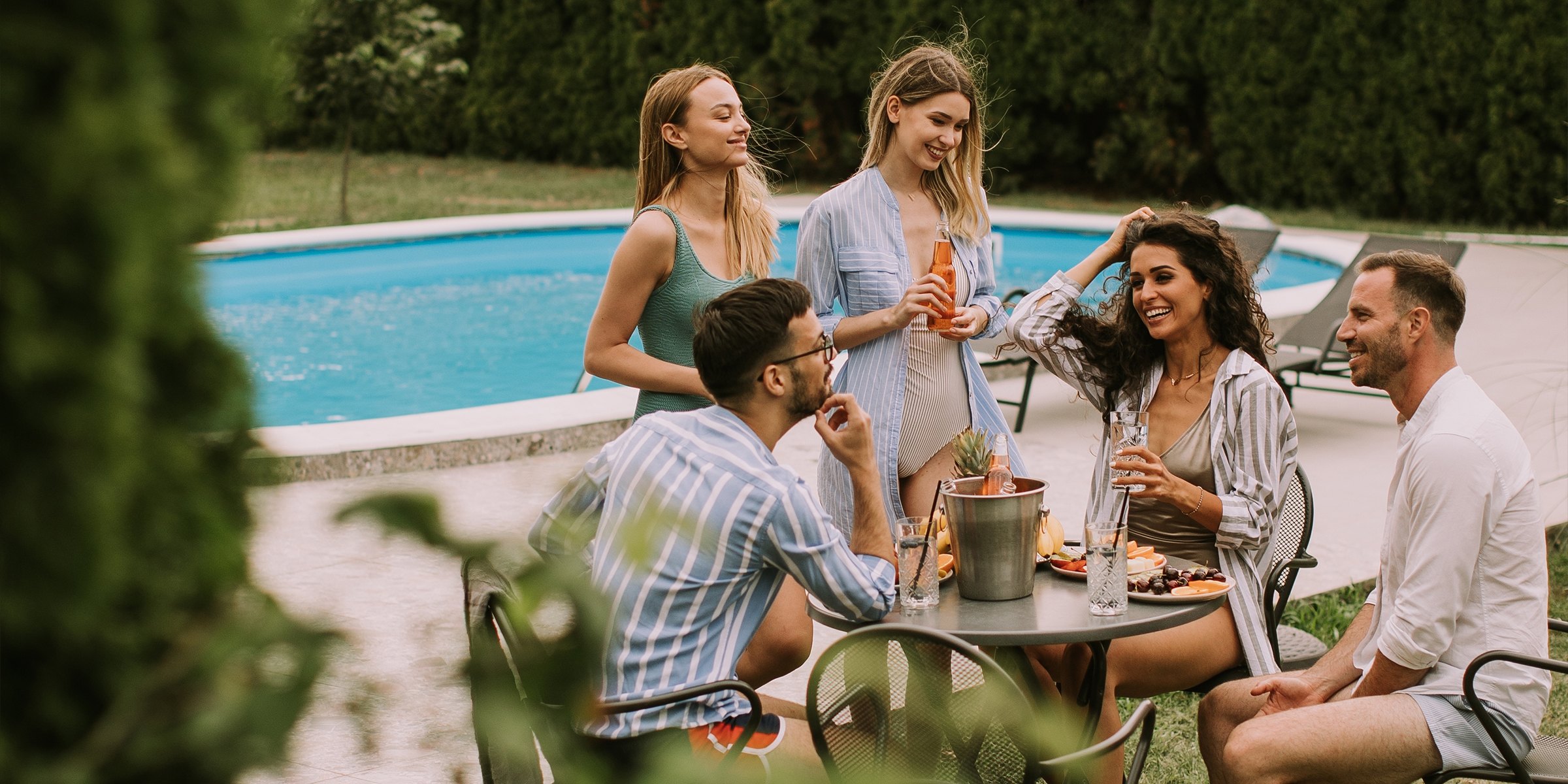 Gente sentada alrededor de una piscina | Fuente: Shutterstock