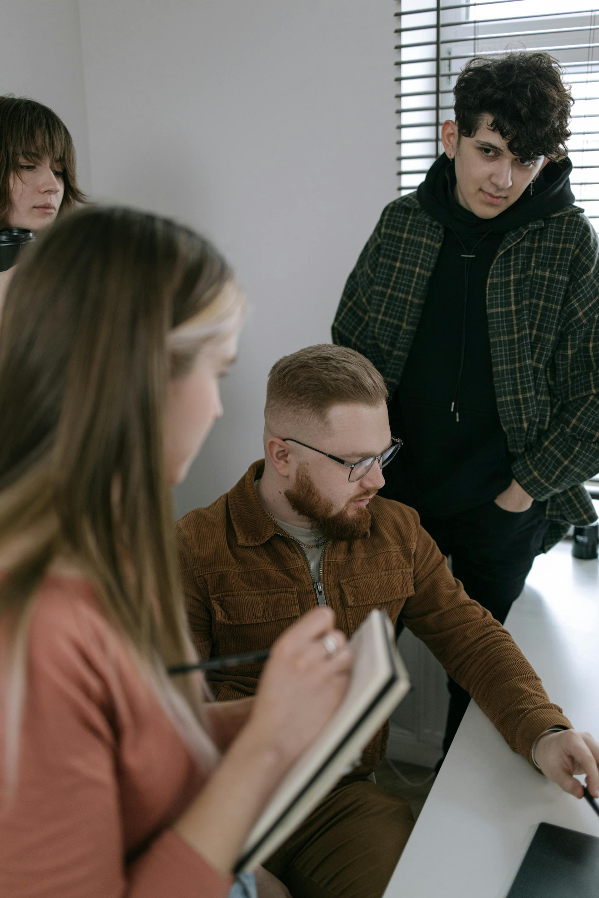 Un joven mira a los demás miembros de su equipo durante la discusión de un proyecto de grupo | Fuente: Pexels