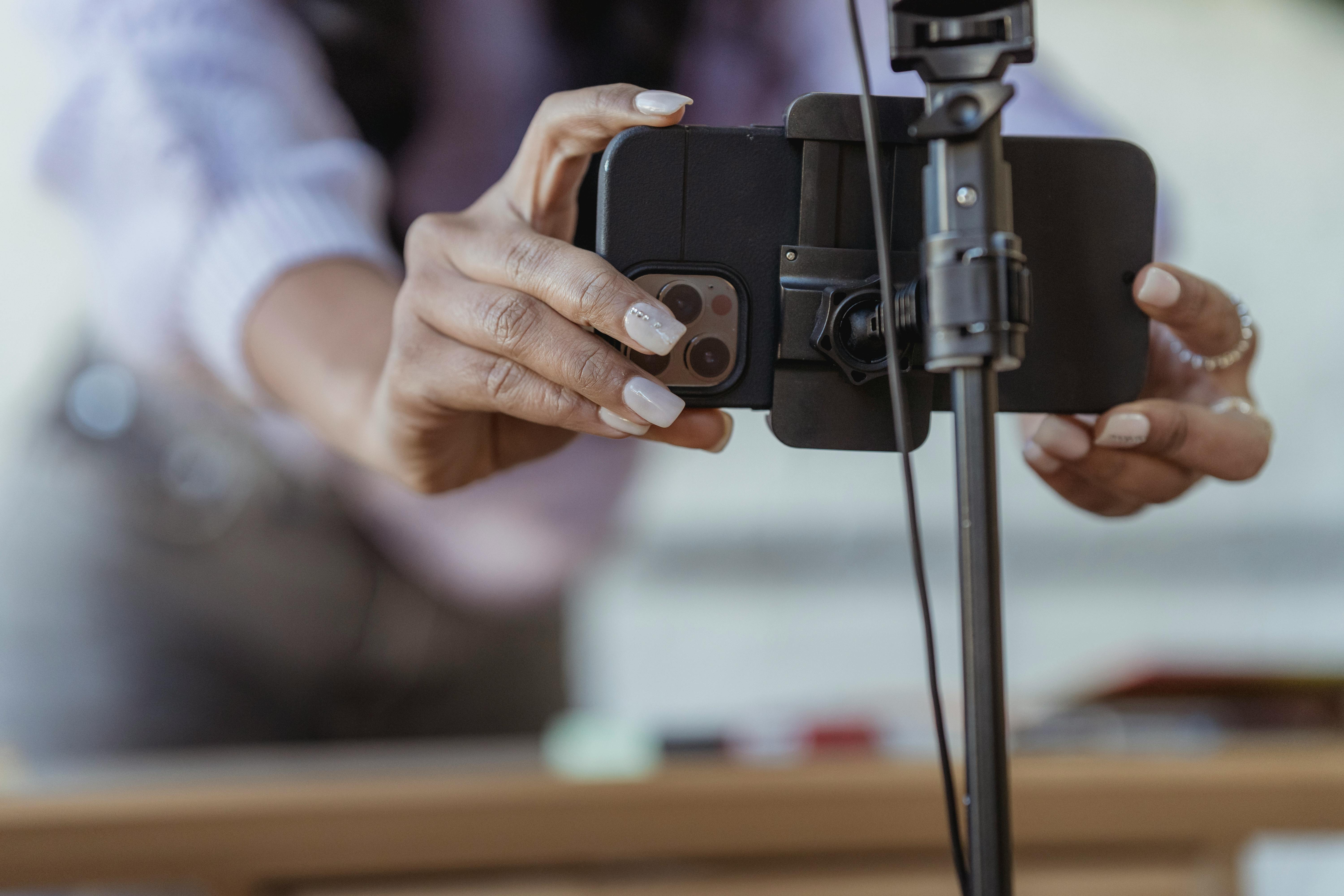 Una mujer ajustando su teléfono en un trípode | Fuente: Pexels