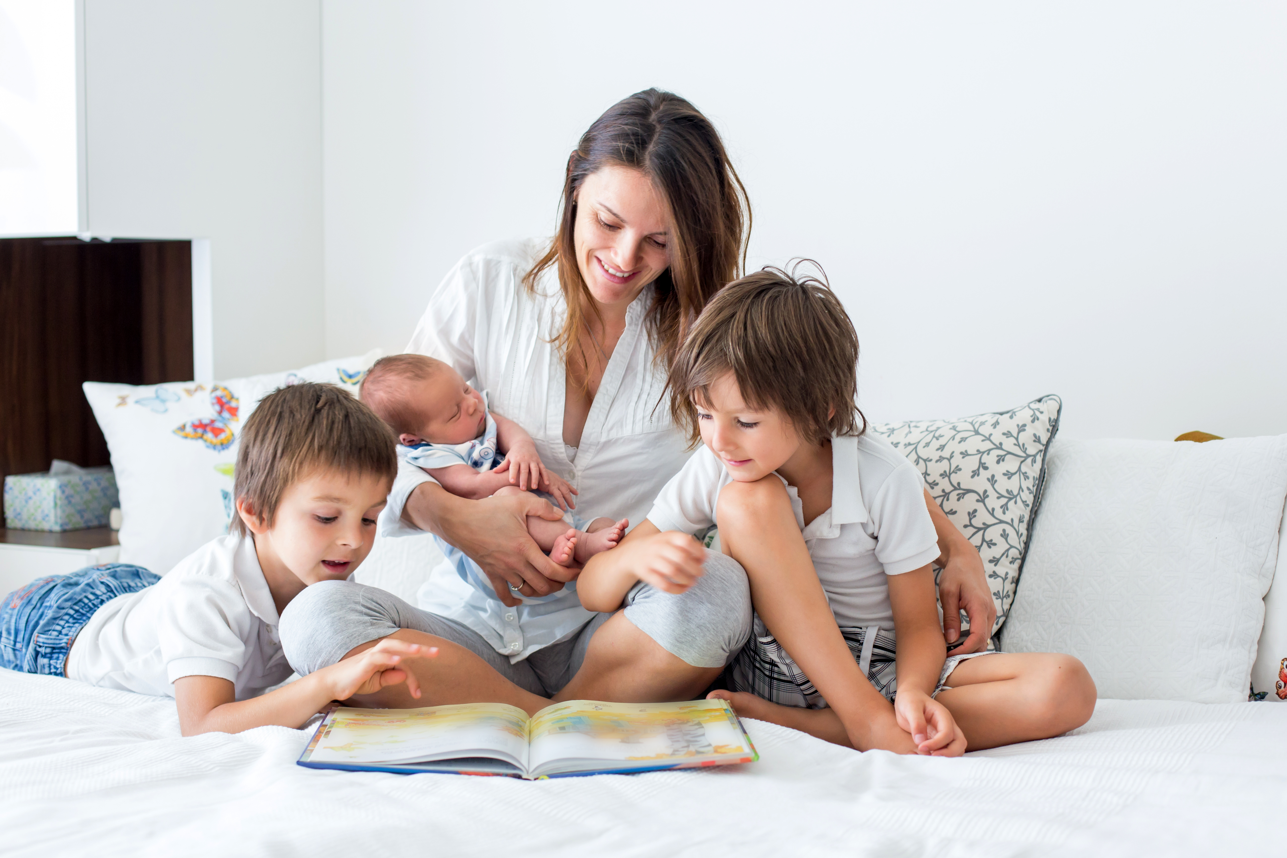 Una joven madre leyendo un libro a sus tres hijos | Foto: Shutterstock