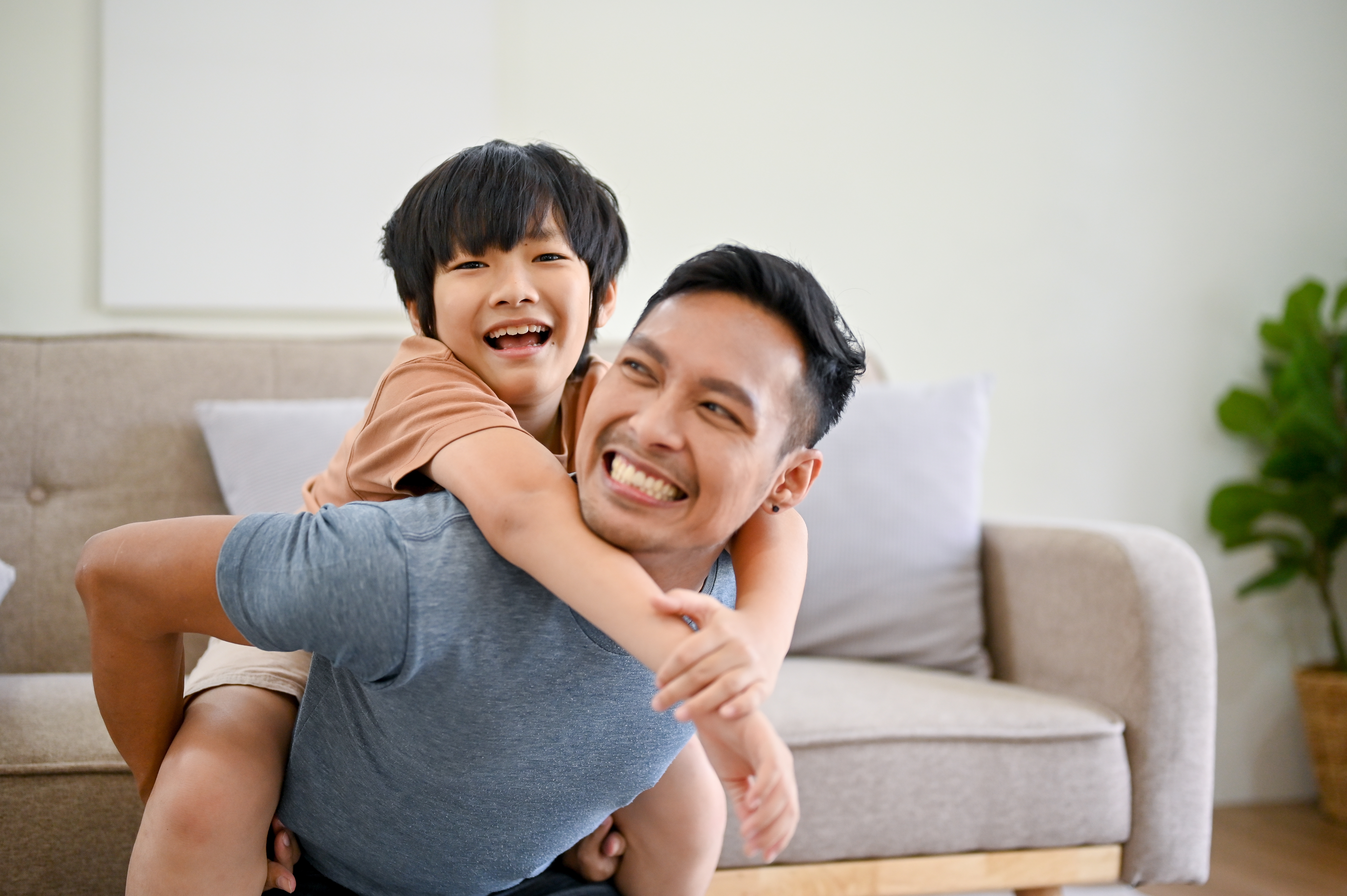 Hijo asiático a la espalda de su padre, sonriendo | Foto: Shutterstock