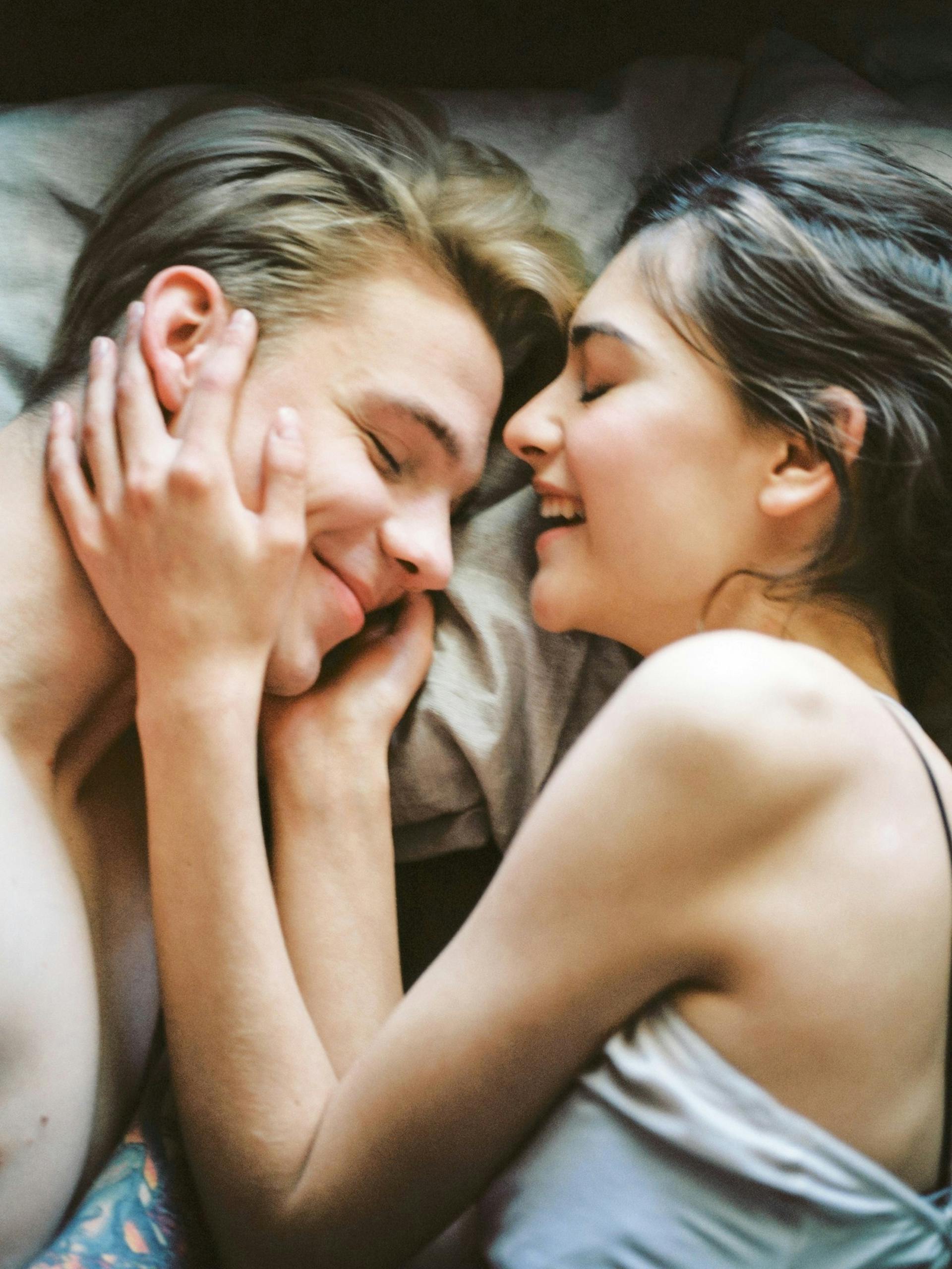 Una pareja feliz tumbada en la cama | Fuente: Pexels