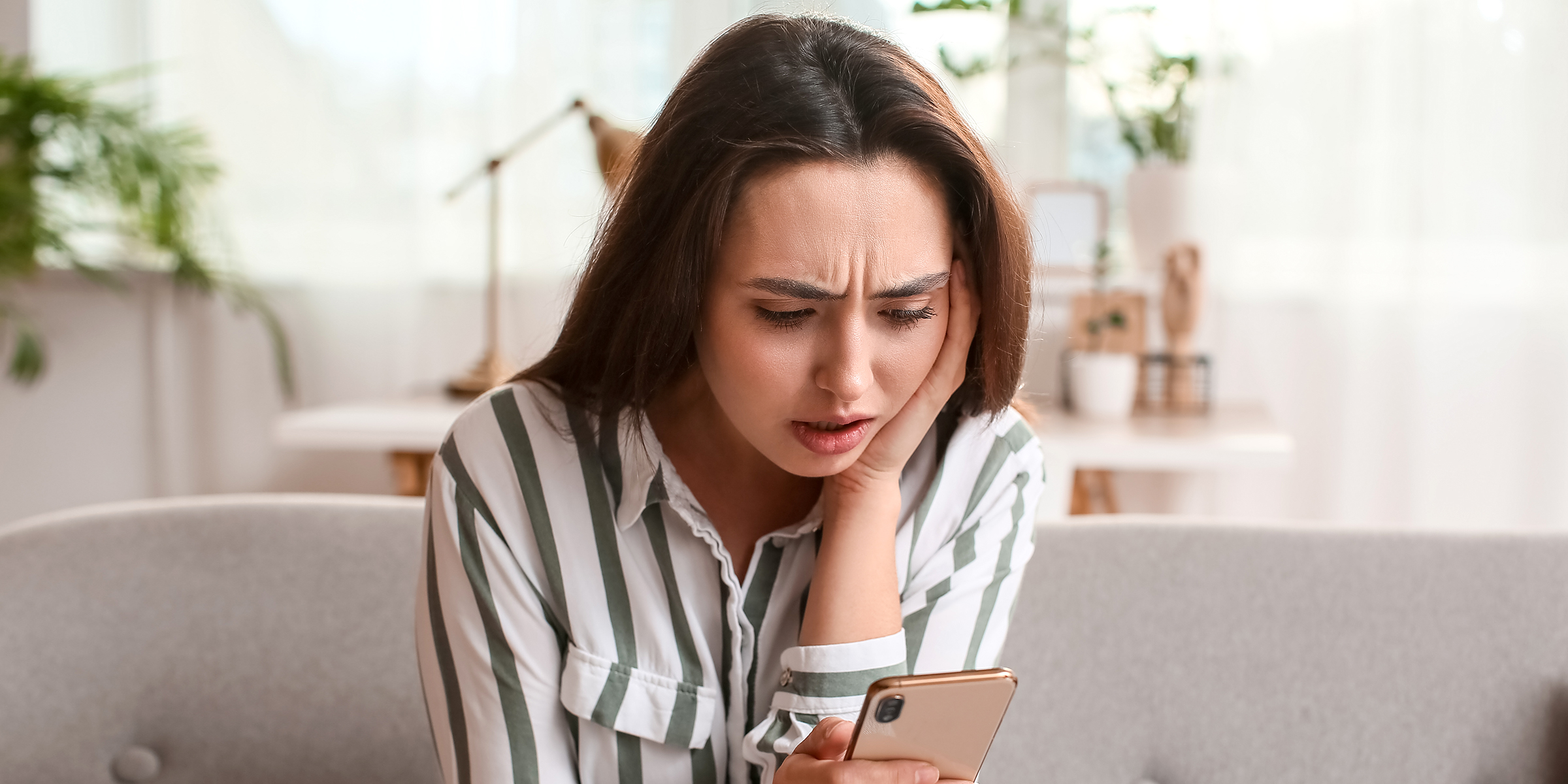 Una mujer conmocionada leyendo un texto en su teléfono | Fuente: Shutterstock