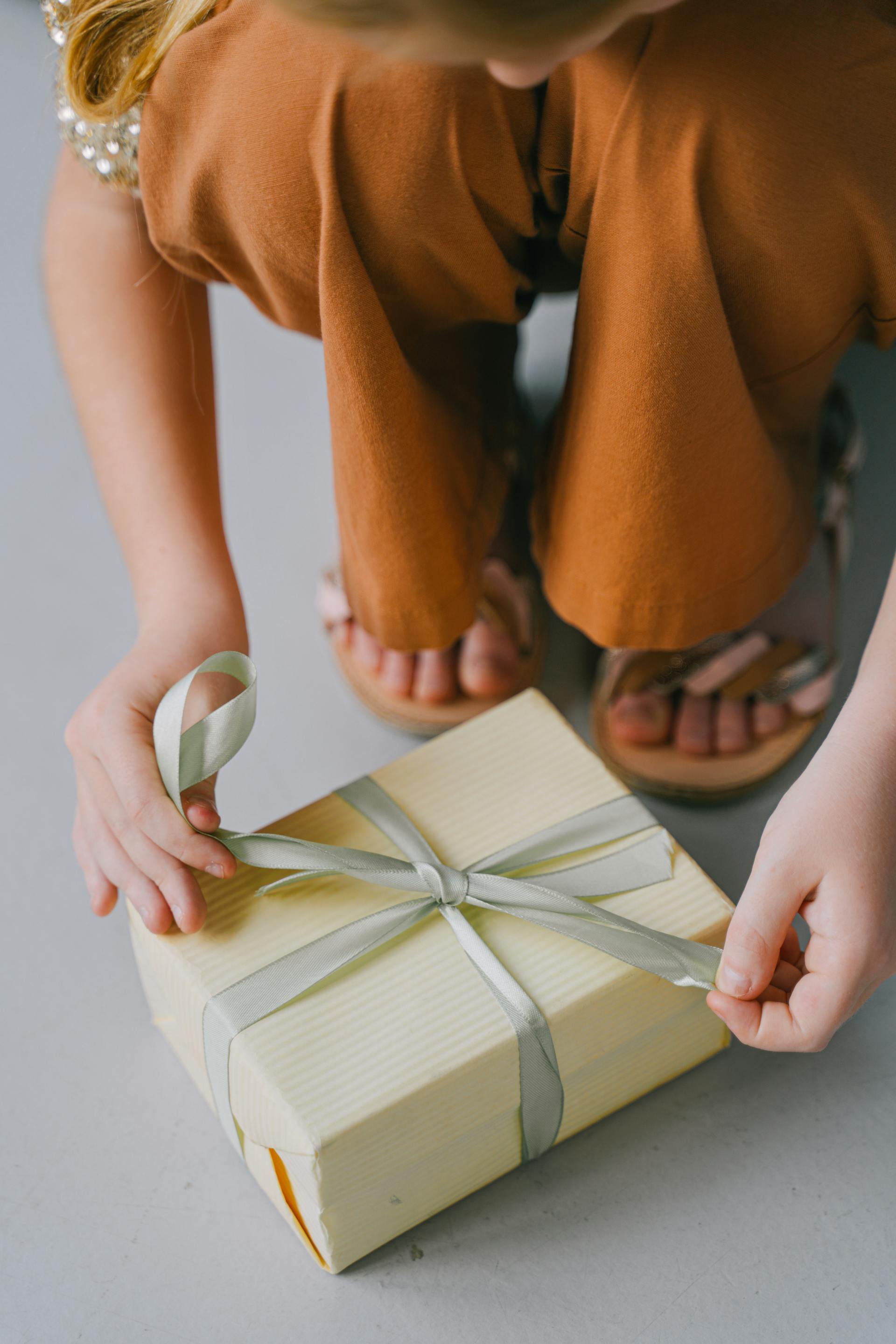 Una mujer atando la cinta de una caja de regalo | Fuente: Pexels