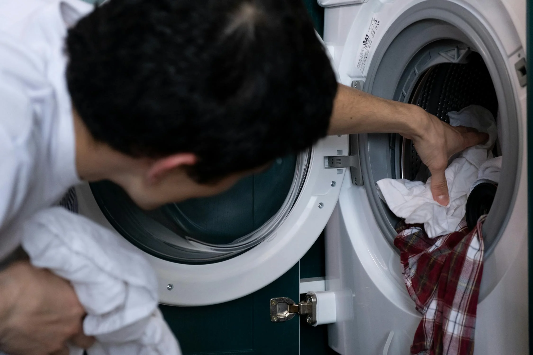 Un hombre cargando la lavadora | Fuente: Pexels