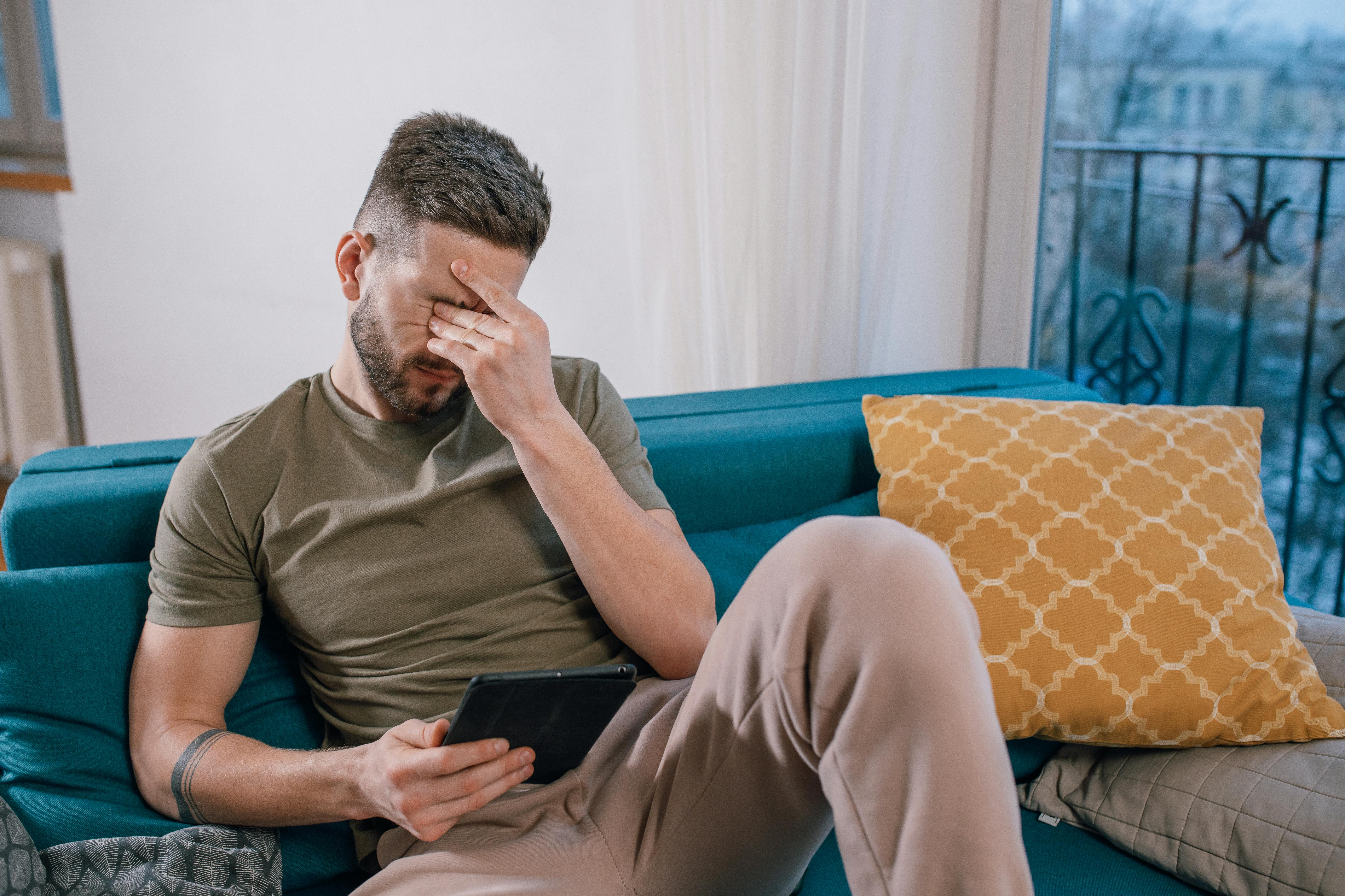 Un hombre llora sentado y mirando algo en una tableta | Foto: Pexels