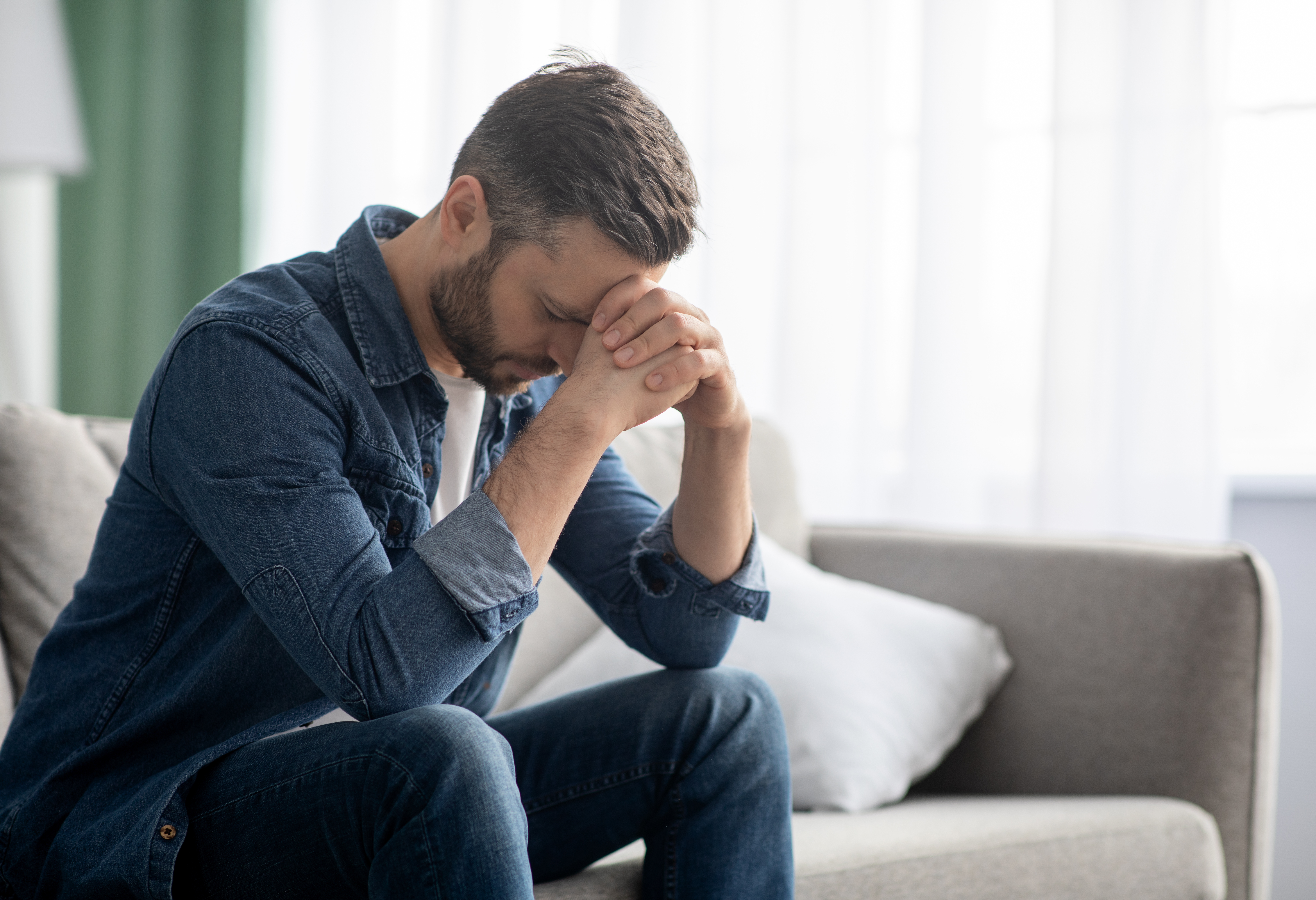 Hombre en un sofá con las manos sobre el rostro | Foto: Shutterstock