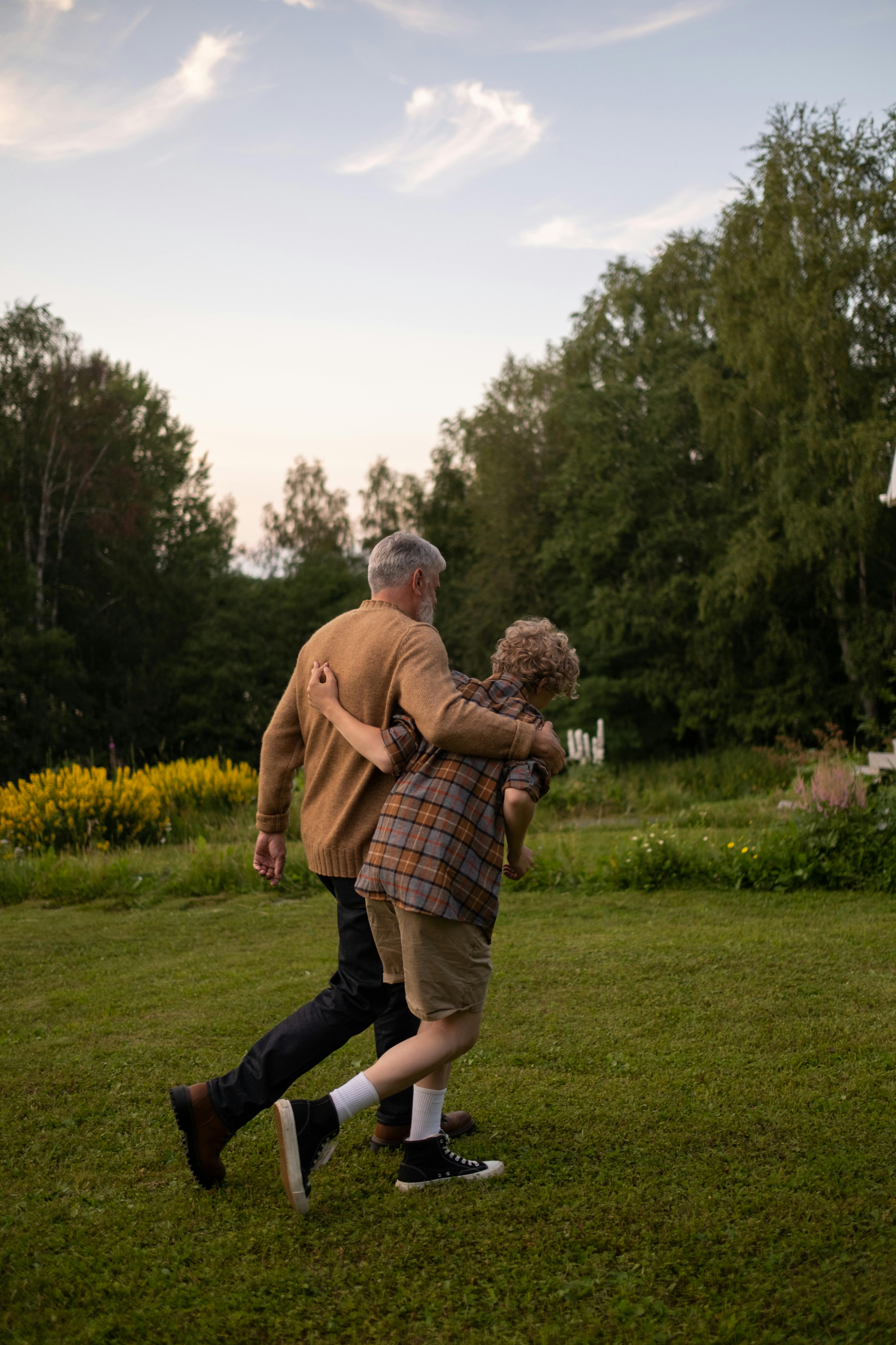 Abuelo y nieto paseando por un jardín | Fuente: Pexels