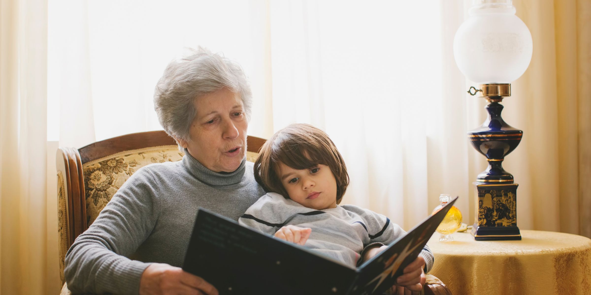Un niño pequeño leyendo un libro con su abuela | Fuente: Getty Images