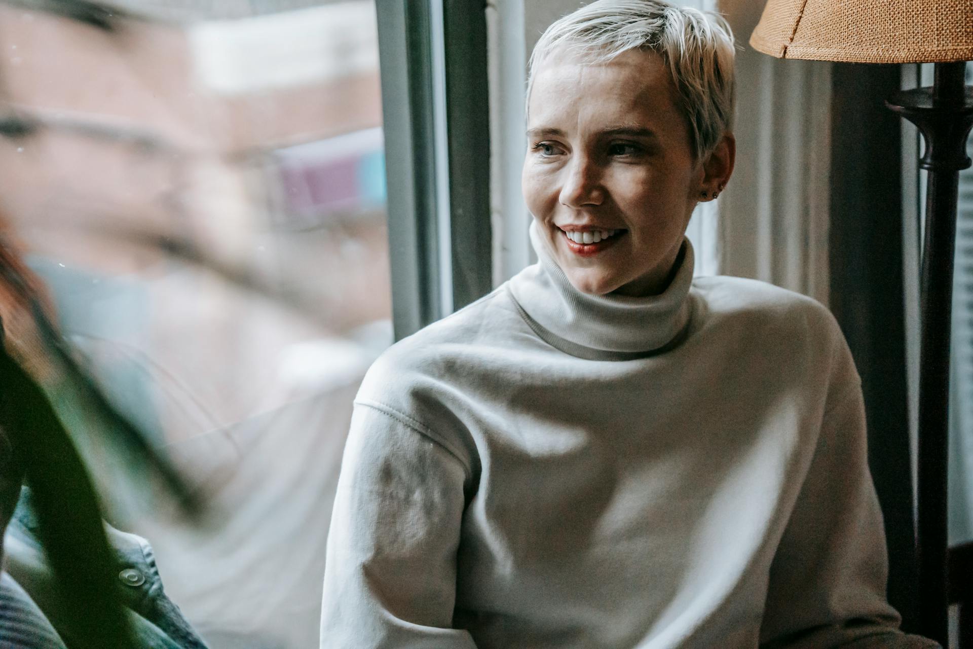 Una mujer sonriendo mientras mira por una ventana | Fuente: Pexels