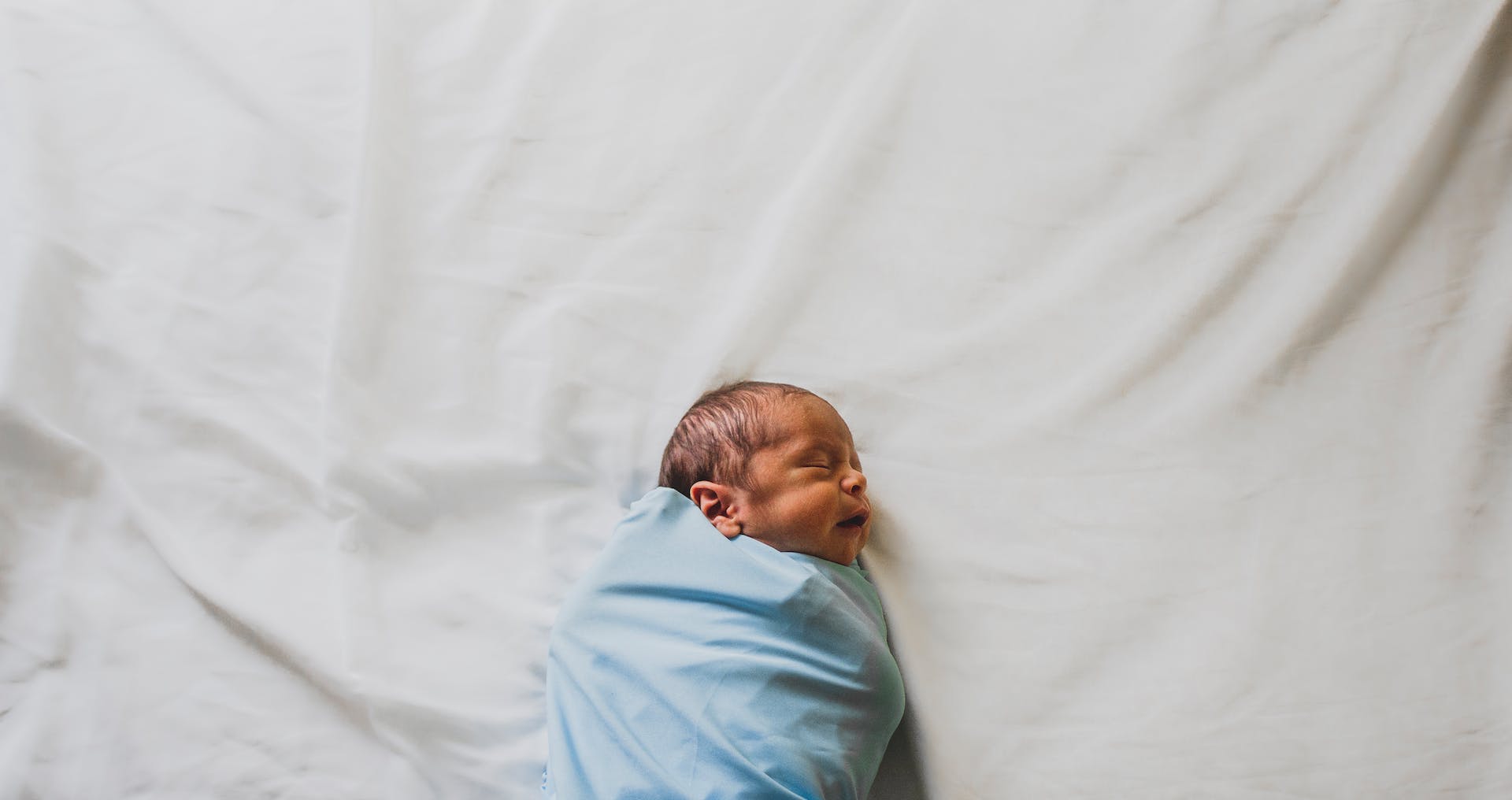 Recién nacido envuelto en una manta azul | Foto: Pexels
