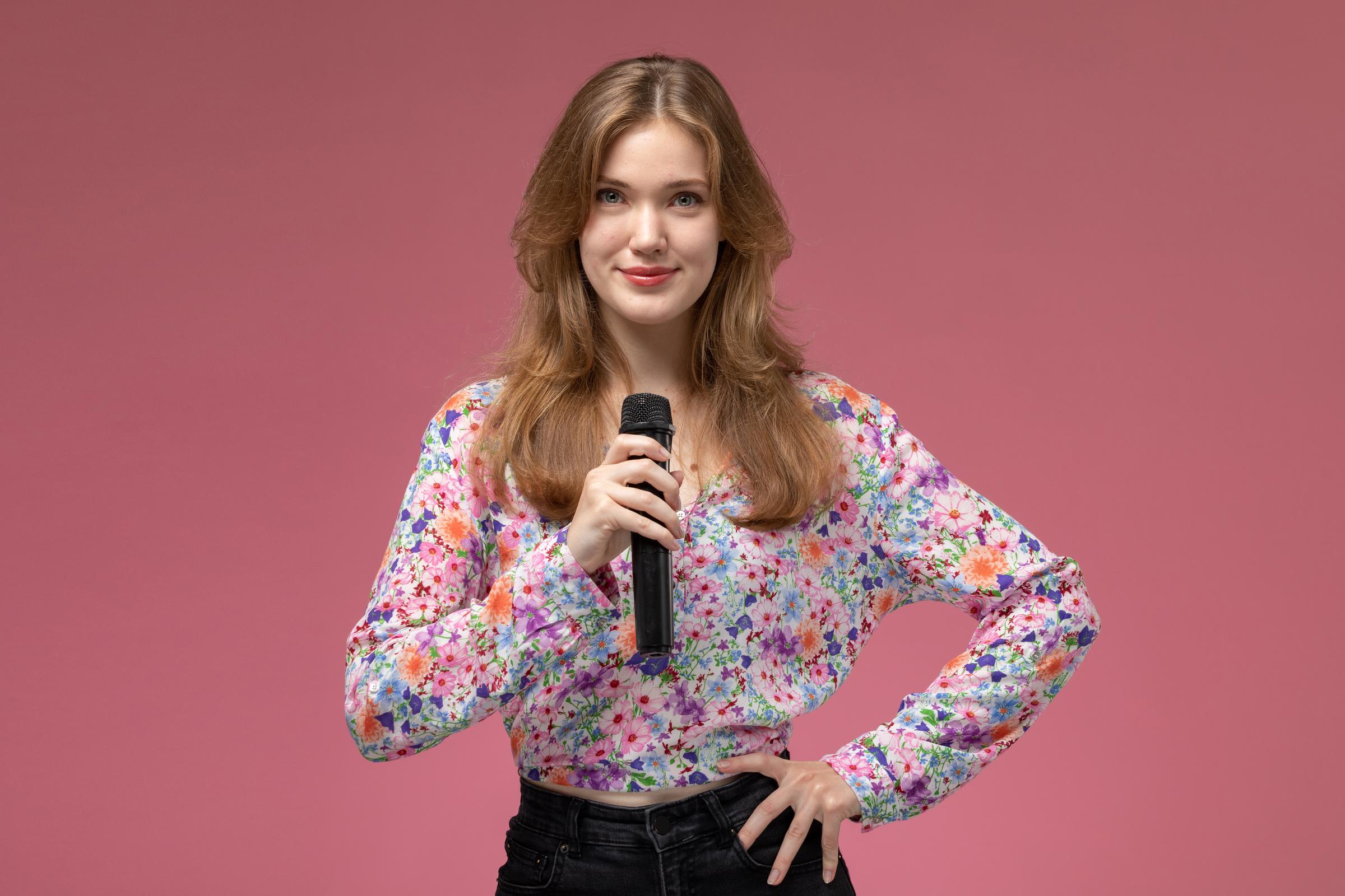 Una mujer sujetando un micrófono | Fuente: Freepik