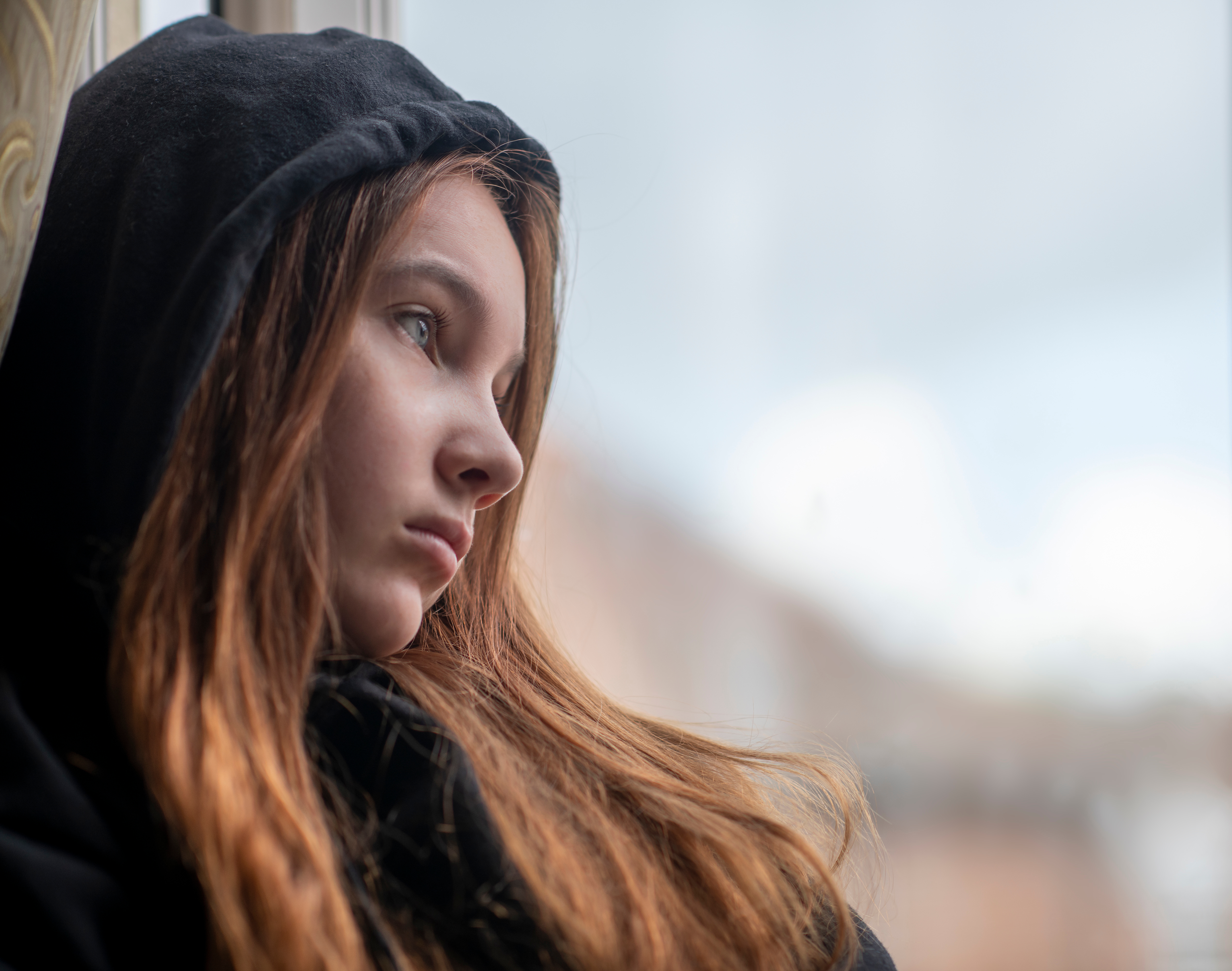 Una adolescente triste junto a una ventana | Fuente: Shutterstock