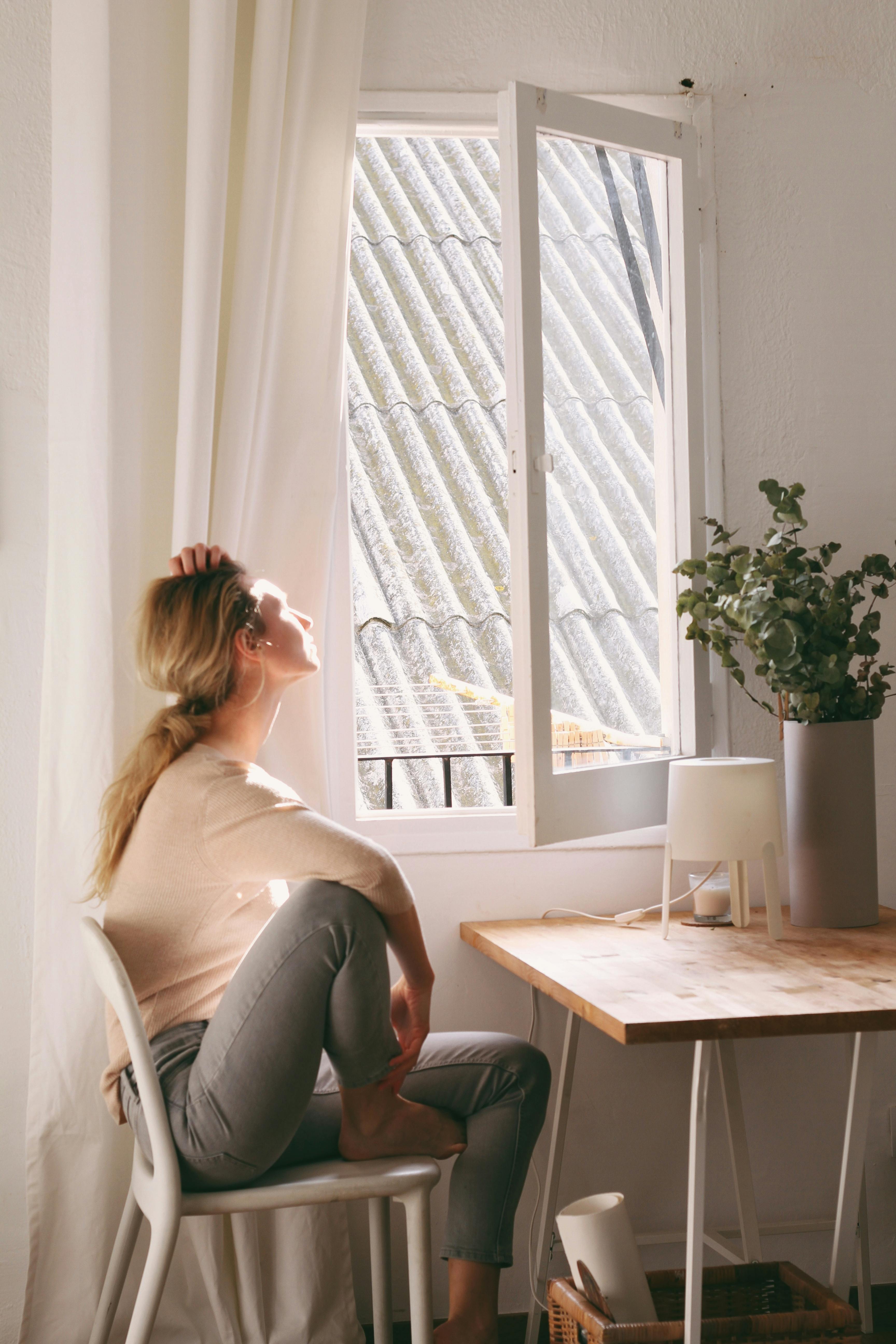 Una joven mirando por la ventana de su Apartamento | Fuente: Pexels