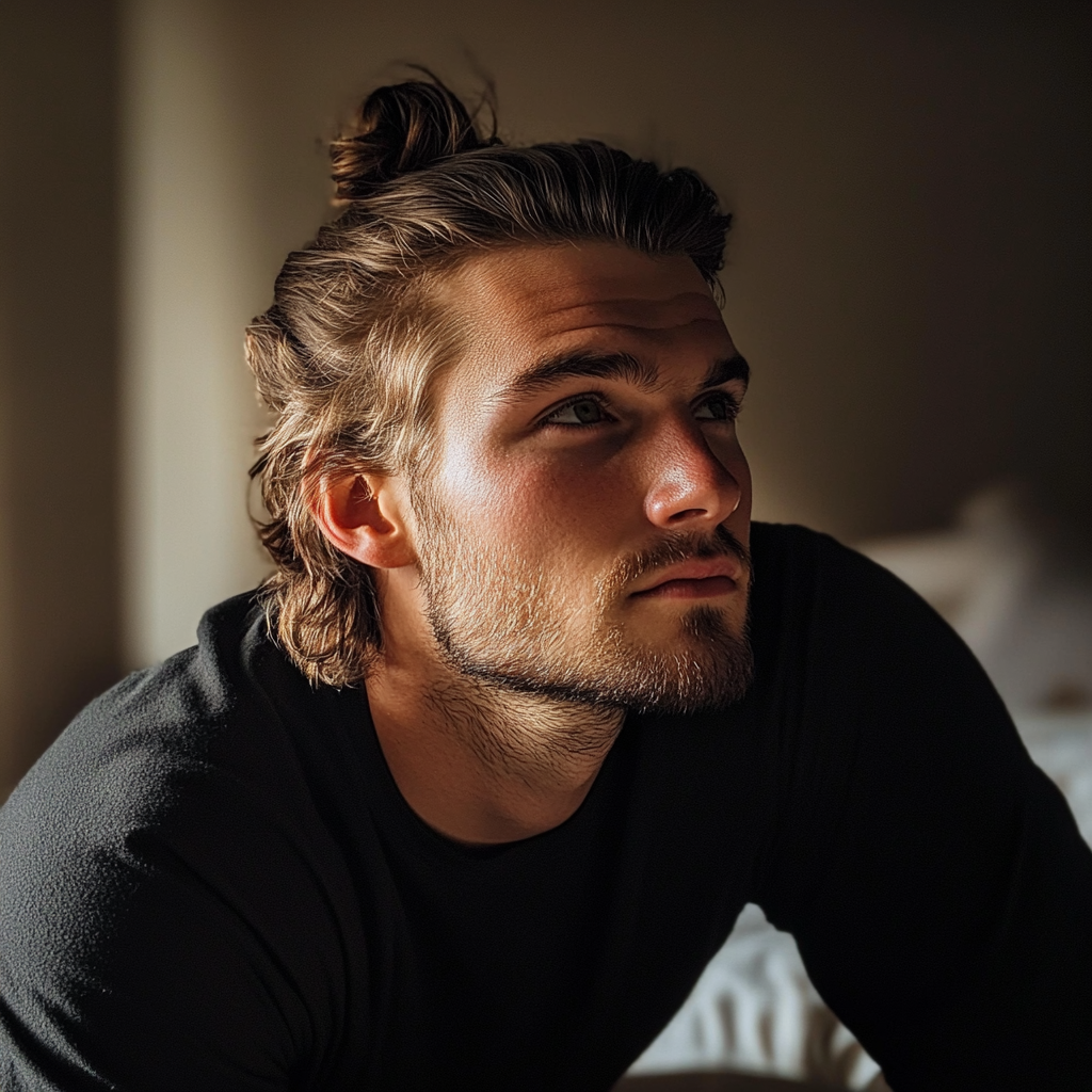 Un hombre sentado en una cama y con mirada pensativa | Fuente: Midjourney