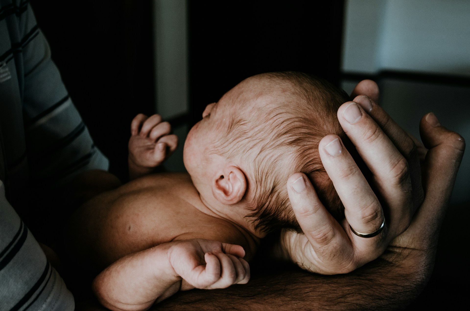 Un hombre emocionalmente abrumado con un bebé recién nacido en brazos | Fuente: Unsplash